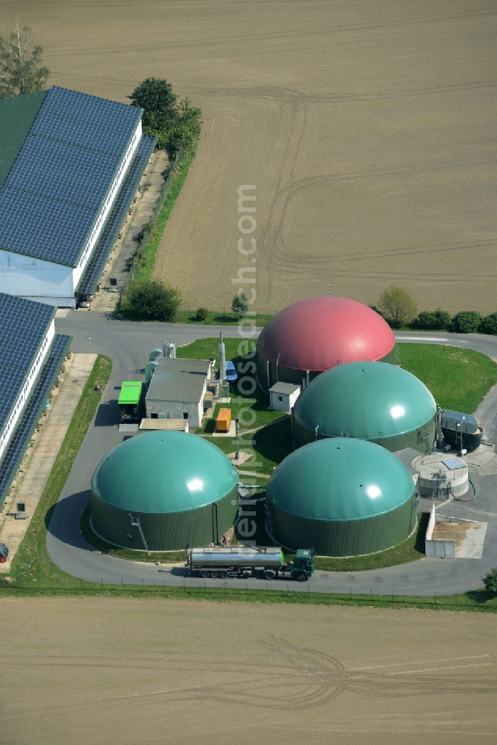 Aerial photograph Ochelmitz - Stables of an agricultural business with biogas plant in the South of Ochelmitz in the state of Saxony. The village is characterised by agricultural estates and farms and is surrounded by fields. The colourful domes of the digester are visible