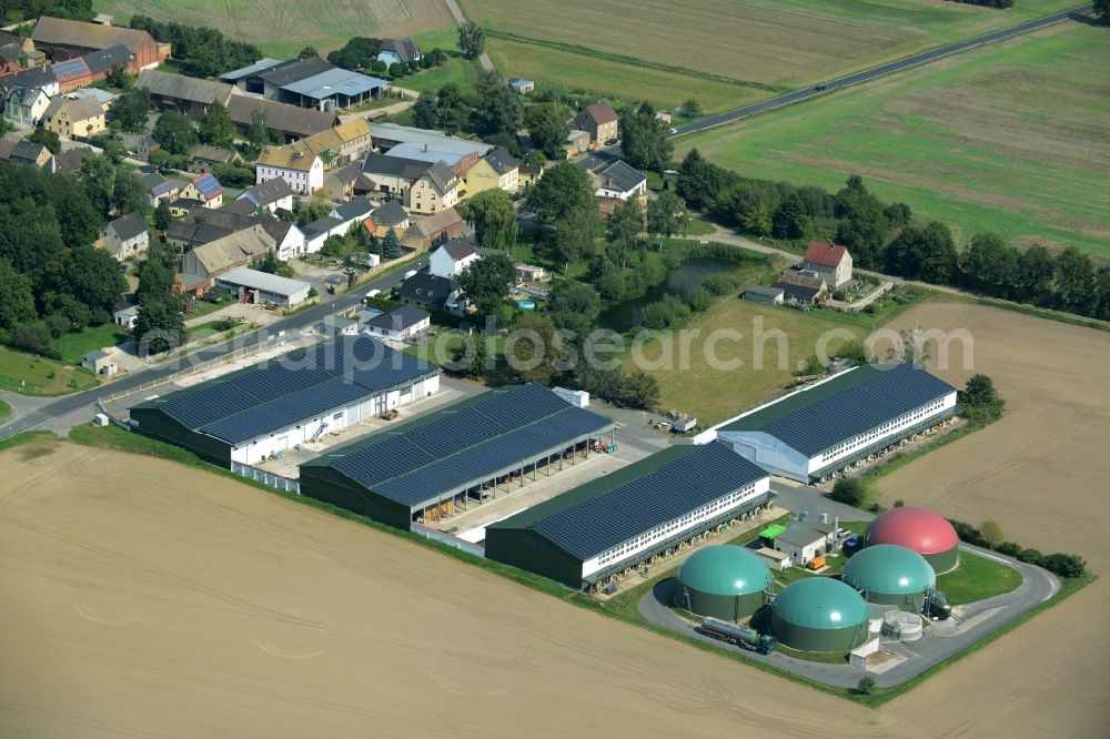 Ochelmitz from above - Stables of an agricultural business with biogas plant in the South of Ochelmitz in the state of Saxony. The village is characterised by agricultural estates and farms and is surrounded by fields. The colourful domes of the digester are visible