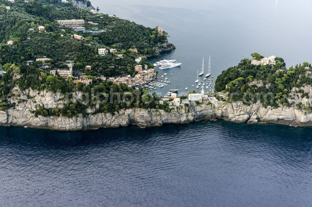 Portofino from above - Cliff coast in Mediterranean Sea with view on the harbor bay in Portofino in Liguria in Italy. The museum Castello Brown stands in the right corner