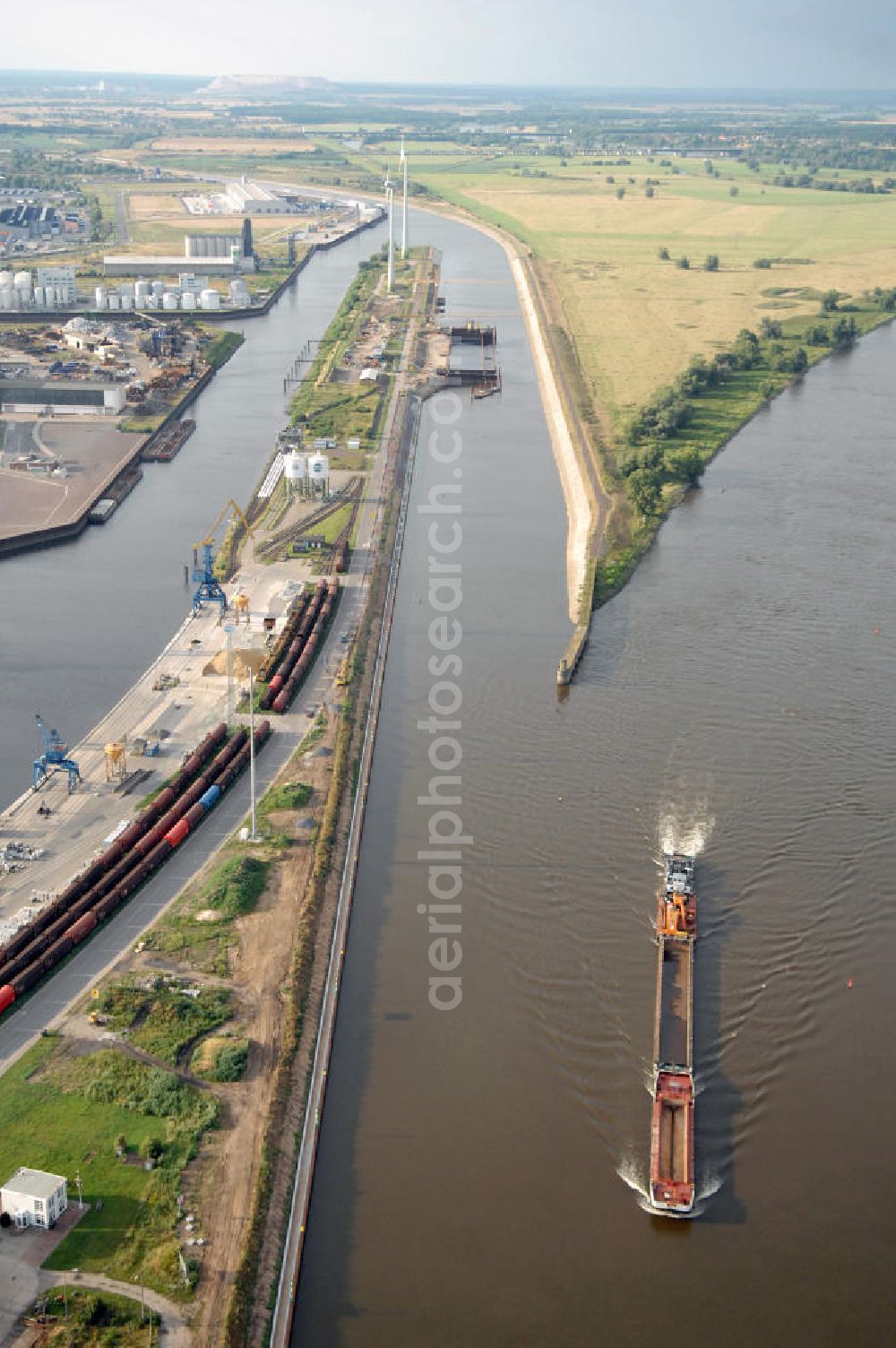 Aerial photograph Magdeburg - Blick auf die Steinkopfinsel im Hafen Magdeburg an der Elbe. Umflossen wird die Steinkopfinsel im Osten von der Elbe und dem Abstiegskanal Rothensee, sowie im Westen vom Zweigkanal Magdeburg. Die Insel ist ca. 2,5 km lang und ca. 0,3 km breit (an der stärksten Stelle). Der Binnenhafen ist in vier Güterumschlagplätze eingeteilt, der Handelshafen, Industriehafen, Kanalhafen und der Hanseshafen. Das Gebiet verteilt sich über die Stadtteile Alte-Neustadt, Industriehafen und Gewerbegebiet Nord. Jedoch hat der Handelshafen für die Schiffahrt heute keine Bedeutung mehr, dieser Bereich wird stetig zum Wissenschaftsstandort umgebaut. Kontakt: Magdeburger Hafen GmbH, Saalestraße 20, 39126 Magdeburg, Tel. +49(0)391 5939-0, Fax +49(0)391 5616648, email: Logistik@magdeburg-hafen.de