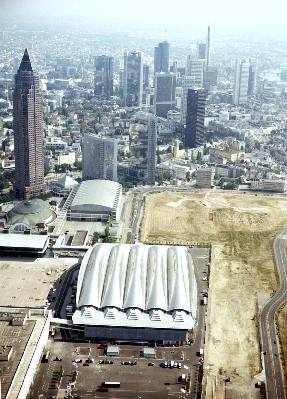 Aerial photograph Frankfurt / M. - Ästhetisch und funktional: Mit den beiden neuen Gebäuden Halle 3 und Forum erweitert die Messe Frankfurt ihr Flächenangebot auf eine Hallenfläche von über 320.000 m2. Hier verbindet sich großzügiges Raumangebot mit innovativer Technik. Die neue Halle 3 gehört zu den derzeit modernsten und schönsten Messehallen Europas. Maße: Grundriss: 220 x 140 m Gebäudehöhe: 43 m Bruttorauminhalt: 826.000 m3 Fassade: 20.000 qm Zwei Veranstaltungsebenen mit einer Bruttoausstellungsfläche von insgesamt rund 38.000m². Bauzeit: 17 Monate Baubeginn: 1. März 2000 Erstnutzung: August 2001 (Tendence)