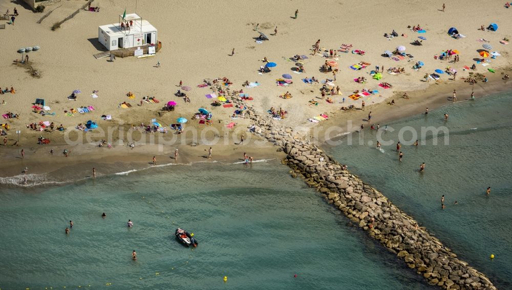 Mauguio from the bird's eye view: Beach lying places and umbrella on the sandy beach landscape of Mauguio on the Mediterranean coast of the province of Languedoc-Roussillon in France