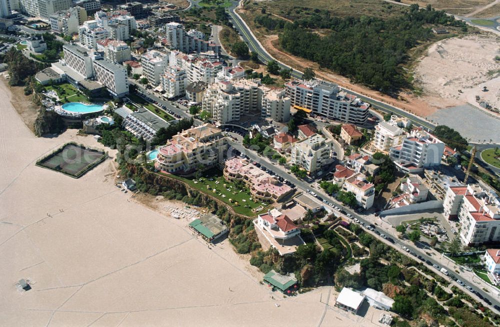 Aerial photograph Praia da Rocha - Blick auf das Strandufer von Praia da Rocha, ein beliebter Strand an der Algarve in Portugal. Er liegt zwischen Portimao und Alvor. Entstanden ist der ca. 1,5 km lange Küstenabschnitt durch die Meeresauswaschung von härteren Felsgestein aus dem sie umgebendem weicheren Material an der hier ca. 20-30 m hohen Steilküste. Oberhalb der Steilkante haben sich zahlreiche Hotels, Ferienwohnungen, Restaurants und Geschäfte den Standortvorteil gesichert.