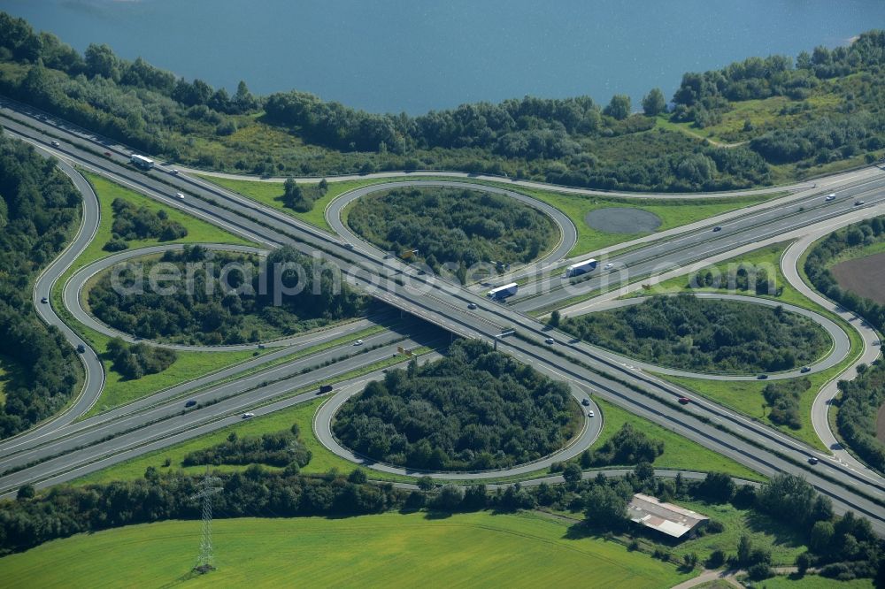 Aerial photograph Minden - Intersection of the federal highways B61 and B65 on the shore of Lake Baltussee in the South of Minden in the state of North Rhine-Westphalia. The clover-leaf intersection is surrounded by trees and meadows and located on the western shore of the lake