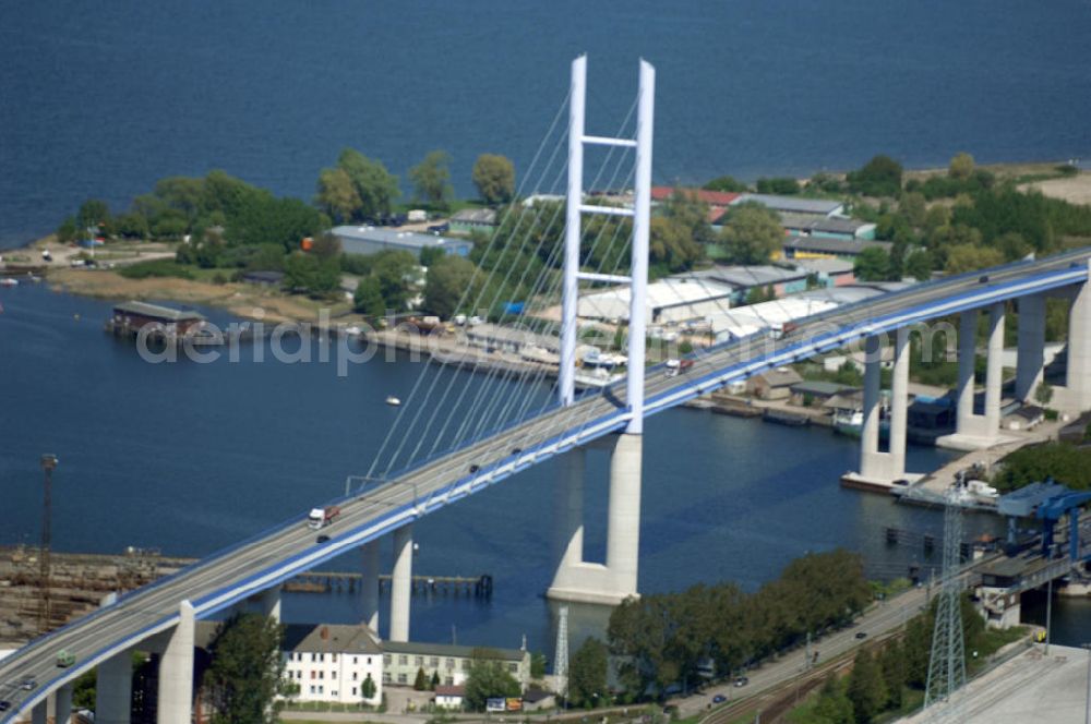 Stralsund from the bird's eye view: Mit dem Begriff Strelasundquerung werden die beiden Brückenverbindungen der Insel Rügen über den Strelasund zum vorpommerschen Festland bei Stralsund, die Rügenbrücke und der Rügendamm, sowie die regelmäßig betriebenen Fährverbindungen zwischen Stralsund und Altefähr sowie Stahlbrode und Glewitz bezeichnet. Der Rügendamm ist die erste feste Strelasundquerung, über den sowohl die alte Bundesstraße 96, als auch eine eingleisige Eisenbahnstrecke sowie ein kombinierter Fuß- und Radweg führen. Sie wurde 1936/1937 fertiggestellt. Rügenbrücke ist der Name der im Jahr 2007 fertiggestellten dreispurigen Hochbrücke ausschließlich für den Kraftfahrzeugverkehr zwischen der Ortschaft Altefähr auf Rügen und der Hanse- und Weltkulturerbestadt Stralsund im Zuge der als Ortsumgehung ausgebauten Bundesstraße 96. Beide Brücken werden parallel betrieben. (DEGES, MAX BÖGL)