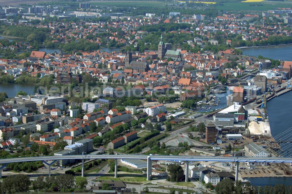 Stralsund from the bird's eye view: Mit dem Begriff Strelasundquerung werden die beiden Brückenverbindungen der Insel Rügen über den Strelasund zum vorpommerschen Festland bei Stralsund, die Rügenbrücke und der Rügendamm, sowie die regelmäßig betriebenen Fährverbindungen zwischen Stralsund und Altefähr sowie Stahlbrode und Glewitz bezeichnet. Der Rügendamm ist die erste feste Strelasundquerung, über den sowohl die alte Bundesstraße 96, als auch eine eingleisige Eisenbahnstrecke sowie ein kombinierter Fuß- und Radweg führen. Sie wurde 1936/1937 fertiggestellt. Rügenbrücke ist der Name der im Jahr 2007 fertiggestellten dreispurigen Hochbrücke ausschließlich für den Kraftfahrzeugverkehr zwischen der Ortschaft Altefähr auf Rügen und der Hanse- und Weltkulturerbestadt Stralsund im Zuge der als Ortsumgehung ausgebauten Bundesstraße 96. Beide Brücken werden parallel betrieben. (DEGES, MAX BÖGL)