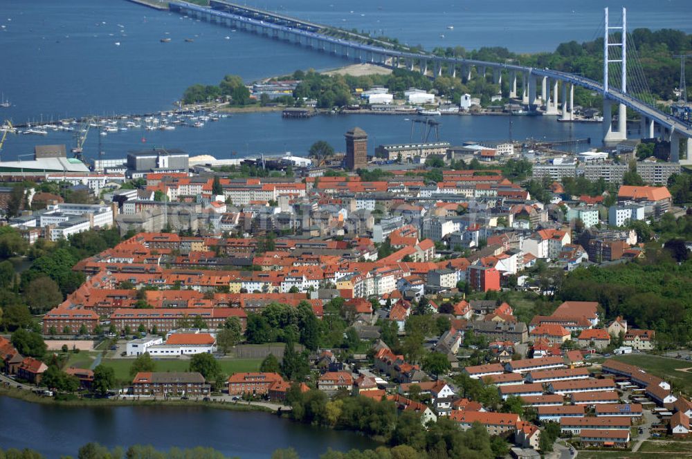 Stralsund from the bird's eye view: Mit dem Begriff Strelasundquerung werden die beiden Brückenverbindungen der Insel Rügen über den Strelasund zum vorpommerschen Festland bei Stralsund, die Rügenbrücke und der Rügendamm, sowie die regelmäßig betriebenen Fährverbindungen zwischen Stralsund und Altefähr sowie Stahlbrode und Glewitz bezeichnet. Der Rügendamm ist die erste feste Strelasundquerung, über den sowohl die alte Bundesstraße 96, als auch eine eingleisige Eisenbahnstrecke sowie ein kombinierter Fuß- und Radweg führen. Sie wurde 1936/1937 fertiggestellt. Rügenbrücke ist der Name der im Jahr 2007 fertiggestellten dreispurigen Hochbrücke ausschließlich für den Kraftfahrzeugverkehr zwischen der Ortschaft Altefähr auf Rügen und der Hanse- und Weltkulturerbestadt Stralsund im Zuge der als Ortsumgehung ausgebauten Bundesstraße 96. Beide Brücken werden parallel betrieben. (DEGES, MAX BÖGL)