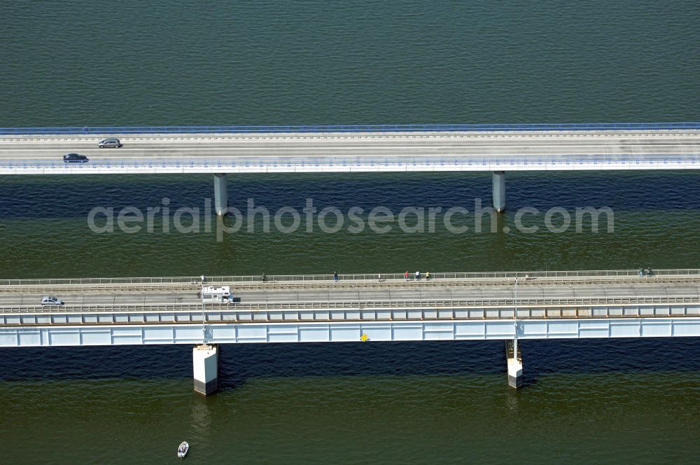 Stralsund from the bird's eye view: Mit dem Begriff Strelasundquerung werden die beiden Brückenverbindungen der Insel Rügen über den Strelasund zum vorpommerschen Festland bei Stralsund, die Rügenbrücke und der Rügendamm, sowie die regelmäßig betriebenen Fährverbindungen zwischen Stralsund und Altefähr sowie Stahlbrode und Glewitz bezeichnet. Der Rügendamm ist die erste feste Strelasundquerung, über den sowohl die alte Bundesstraße 96, als auch eine eingleisige Eisenbahnstrecke sowie ein kombinierter Fuß- und Radweg führen. Sie wurde 1936/1937 fertiggestellt. Rügenbrücke ist der Name der im Jahr 2007 fertiggestellten dreispurigen Hochbrücke ausschließlich für den Kraftfahrzeugverkehr zwischen der Ortschaft Altefähr auf Rügen und der Hanse- und Weltkulturerbestadt Stralsund im Zuge der als Ortsumgehung ausgebauten Bundesstraße 96. Beide Brücken werden parallel betrieben. (DEGES, MAX BÖGL)