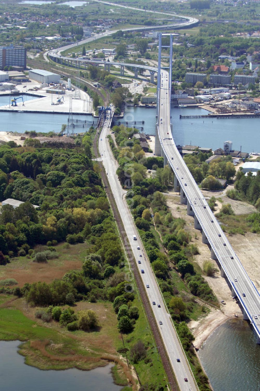 Stralsund from above - Mit dem Begriff Strelasundquerung werden die beiden Brückenverbindungen der Insel Rügen über den Strelasund zum vorpommerschen Festland bei Stralsund, die Rügenbrücke und der Rügendamm, sowie die regelmäßig betriebenen Fährverbindungen zwischen Stralsund und Altefähr sowie Stahlbrode und Glewitz bezeichnet. Der Rügendamm ist die erste feste Strelasundquerung, über den sowohl die alte Bundesstraße 96, als auch eine eingleisige Eisenbahnstrecke sowie ein kombinierter Fuß- und Radweg führen. Sie wurde 1936/1937 fertiggestellt. Rügenbrücke ist der Name der im Jahr 2007 fertiggestellten dreispurigen Hochbrücke ausschließlich für den Kraftfahrzeugverkehr zwischen der Ortschaft Altefähr auf Rügen und der Hanse- und Weltkulturerbestadt Stralsund im Zuge der als Ortsumgehung ausgebauten Bundesstraße 96. Beide Brücken werden parallel betrieben. (DEGES, MAX BÖGL)