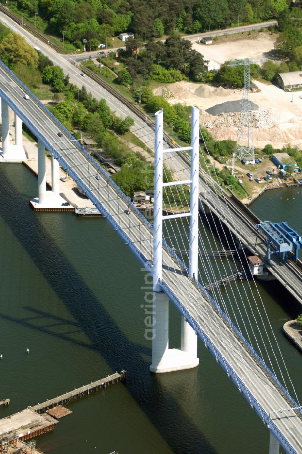 Stralsund from the bird's eye view: Mit dem Begriff Strelasundquerung werden die beiden Brückenverbindungen der Insel Rügen über den Strelasund zum vorpommerschen Festland bei Stralsund, die Rügenbrücke und der Rügendamm, sowie die regelmäßig betriebenen Fährverbindungen zwischen Stralsund und Altefähr sowie Stahlbrode und Glewitz bezeichnet. Der Rügendamm ist die erste feste Strelasundquerung, über den sowohl die alte Bundesstraße 96, als auch eine eingleisige Eisenbahnstrecke sowie ein kombinierter Fuß- und Radweg führen. Sie wurde 1936/1937 fertiggestellt. Rügenbrücke ist der Name der im Jahr 2007 fertiggestellten dreispurigen Hochbrücke ausschließlich für den Kraftfahrzeugverkehr zwischen der Ortschaft Altefähr auf Rügen und der Hanse- und Weltkulturerbestadt Stralsund im Zuge der als Ortsumgehung ausgebauten Bundesstraße 96. Beide Brücken werden parallel betrieben. (DEGES, MAX BÖGL)