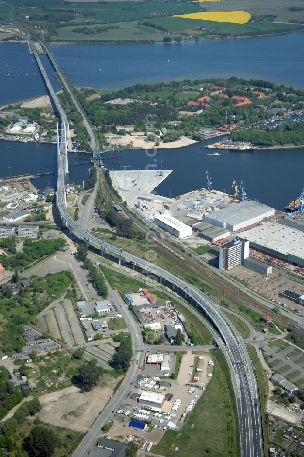 Aerial photograph Stralsund - Mit dem Begriff Strelasundquerung werden die beiden Brückenverbindungen der Insel Rügen über den Strelasund zum vorpommerschen Festland bei Stralsund, die Rügenbrücke und der Rügendamm, sowie die regelmäßig betriebenen Fährverbindungen zwischen Stralsund und Altefähr sowie Stahlbrode und Glewitz bezeichnet. Der Rügendamm ist die erste feste Strelasundquerung, über den sowohl die alte Bundesstraße 96, als auch eine eingleisige Eisenbahnstrecke sowie ein kombinierter Fuß- und Radweg führen. Sie wurde 1936/1937 fertiggestellt. Rügenbrücke ist der Name der im Jahr 2007 fertiggestellten dreispurigen Hochbrücke ausschließlich für den Kraftfahrzeugverkehr zwischen der Ortschaft Altefähr auf Rügen und der Hanse- und Weltkulturerbestadt Stralsund im Zuge der als Ortsumgehung ausgebauten Bundesstraße 96. Beide Brücken werden parallel betrieben. (DEGES, MAX BÖGL)