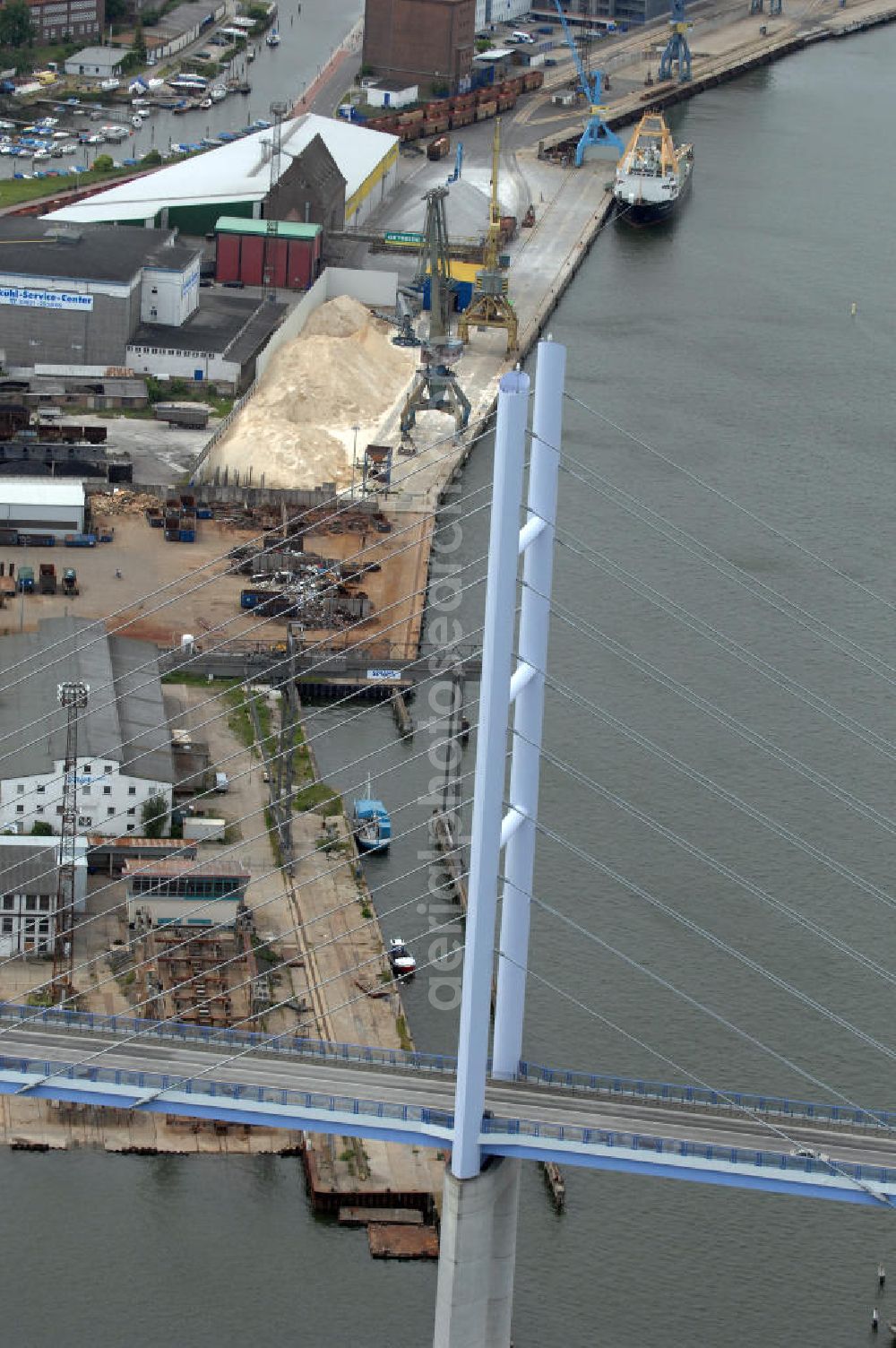 Stralsund from the bird's eye view: Mit dem Begriff Strelasundquerung werden die beiden Brückenverbindungen der Insel Rügen über den Strelasund zum vorpommerschen Festland bei Stralsund, die Rügenbrücke und der Rügendamm , sowie die regelmäßig betriebenen Fährverbindungen zwischen Stralsund und Altefähr sowie Stahlbrode und Glewitz bezeichnet. Der Rügendamm ist die erste feste Strelasundquerung, über den sowohl die alte Bundesstraße 96, als auch eine eingleisige Eisenbahnstrecke sowie ein kombinierter Fuß- und Radweg führen. Sie wurde 1936/1937 fertiggestellt. Rügenbrücke ist der Name der im Jahr 2007 fertiggestellten dreispurigen Hochbrücke ausschließlich für den Kraftfahrzeugverkehr zwischen der Ortschaft Altefähr auf Rügen und der Hanse- und Weltkulturerbestadt Stralsund im Zuge der als Ortsumgehung ausgebauten Bundesstraße 96. Beide Brücken werden parallel betrieben. (DEGES, MAX BÖGL)