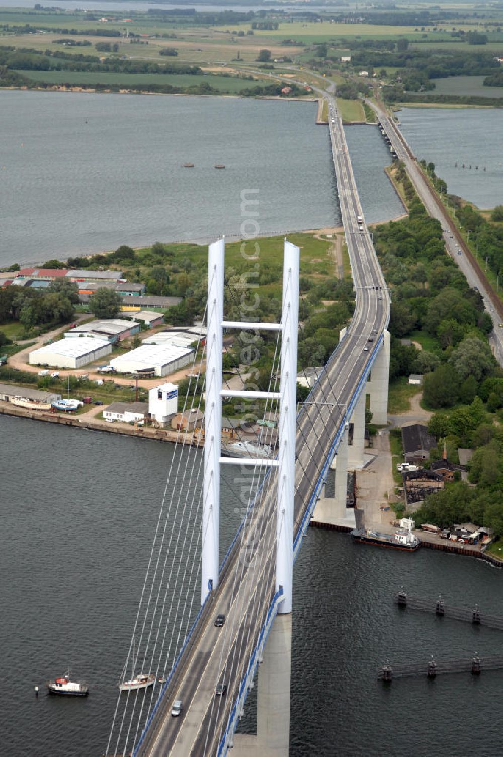 Aerial image Stralsund - Mit dem Begriff Strelasundquerung werden die beiden Brückenverbindungen der Insel Rügen über den Strelasund zum vorpommerschen Festland bei Stralsund, die Rügenbrücke und der Rügendamm , sowie die regelmäßig betriebenen Fährverbindungen zwischen Stralsund und Altefähr sowie Stahlbrode und Glewitz bezeichnet. Der Rügendamm ist die erste feste Strelasundquerung, über den sowohl die alte Bundesstraße 96, als auch eine eingleisige Eisenbahnstrecke sowie ein kombinierter Fuß- und Radweg führen. Sie wurde 1936/1937 fertiggestellt. Rügenbrücke ist der Name der im Jahr 2007 fertiggestellten dreispurigen Hochbrücke ausschließlich für den Kraftfahrzeugverkehr zwischen der Ortschaft Altefähr auf Rügen und der Hanse- und Weltkulturerbestadt Stralsund im Zuge der als Ortsumgehung ausgebauten Bundesstraße 96. Beide Brücken werden parallel betrieben. (DEGES, MAX BÖGL)