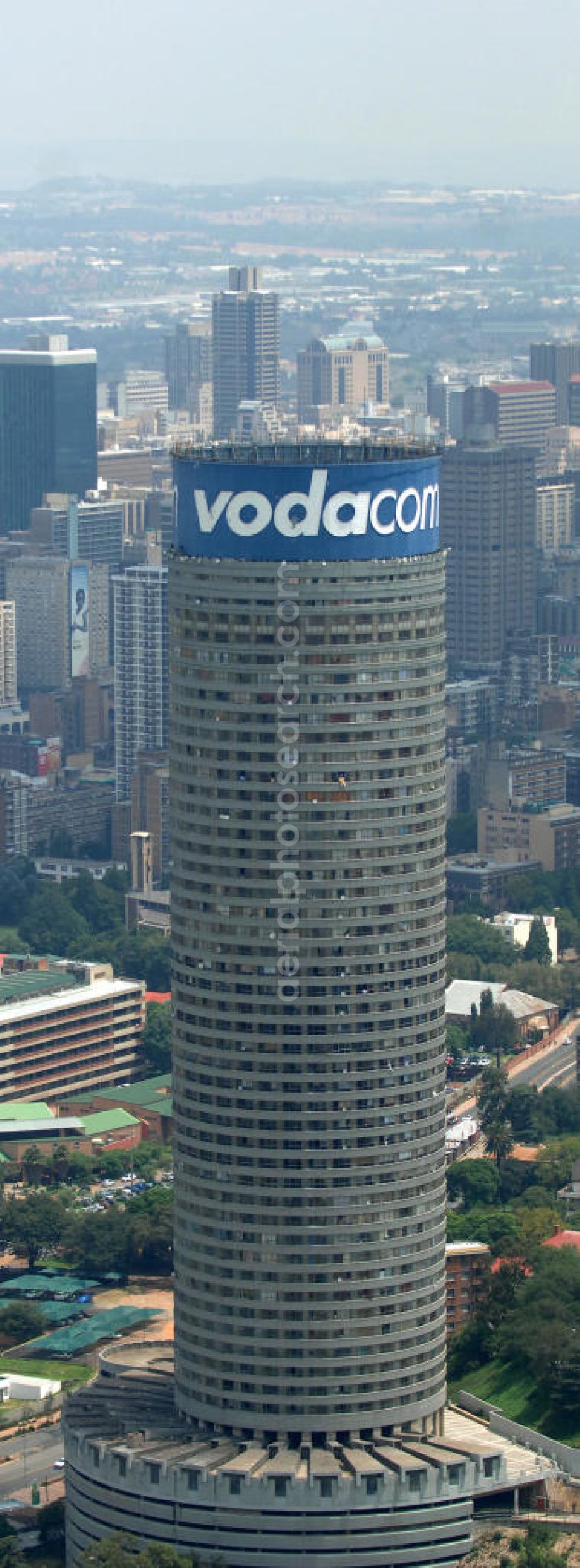 Aerial photograph Johannesburg - Blick auf den Strydom Tower (Ponte City Apartments) an der Saratoga Ace / Joe Slovo Dr in Johannesburg. Das Hochhaus ist durch seine weithin sichtbare vodacom - Leuchtreklame erkennbar und ein Markenzeichen der Stadt. View of the Strydom Tower (Ponte City Apartments) at the Saratoga Ace / Joe Slovo Dr in Johannesburg. The skyscraper is visible for miles vodacom through his - neon sign and a recognizable brand in the city.