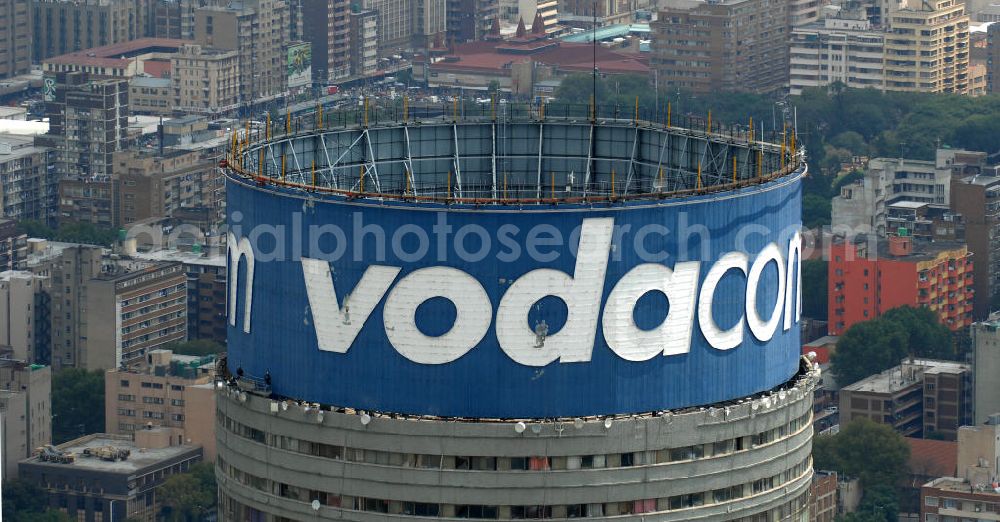 Aerial photograph Johannesburg - Blick auf den Strydom Tower (Ponte City Apartments) an der Saratoga Ace / Joe Slovo Dr in Johannesburg. Das Hochhaus ist durch seine weithin sichtbare vodacom - Leuchtreklame erkennbar und ein Markenzeichen der Stadt. View of the Strydom Tower (Ponte City Apartments) at the Saratoga Ace / Joe Slovo Dr in Johannesburg. The skyscraper is visible for miles vodacom through his - neon sign and a recognizable brand in the city.