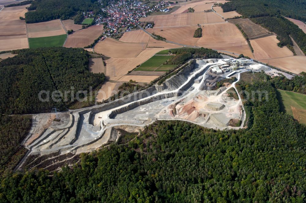 Gössenheim from the bird's eye view: Grounds and overburden surfaces open pit mining and building material works of the companies Kalkstein-Schottertwerk Goessenheim GmbH & Co. KG and AMS Asphaltmischwerke Main-Saale GmbH + Co. KG in Goessenheim in the state Bavaria, Germany