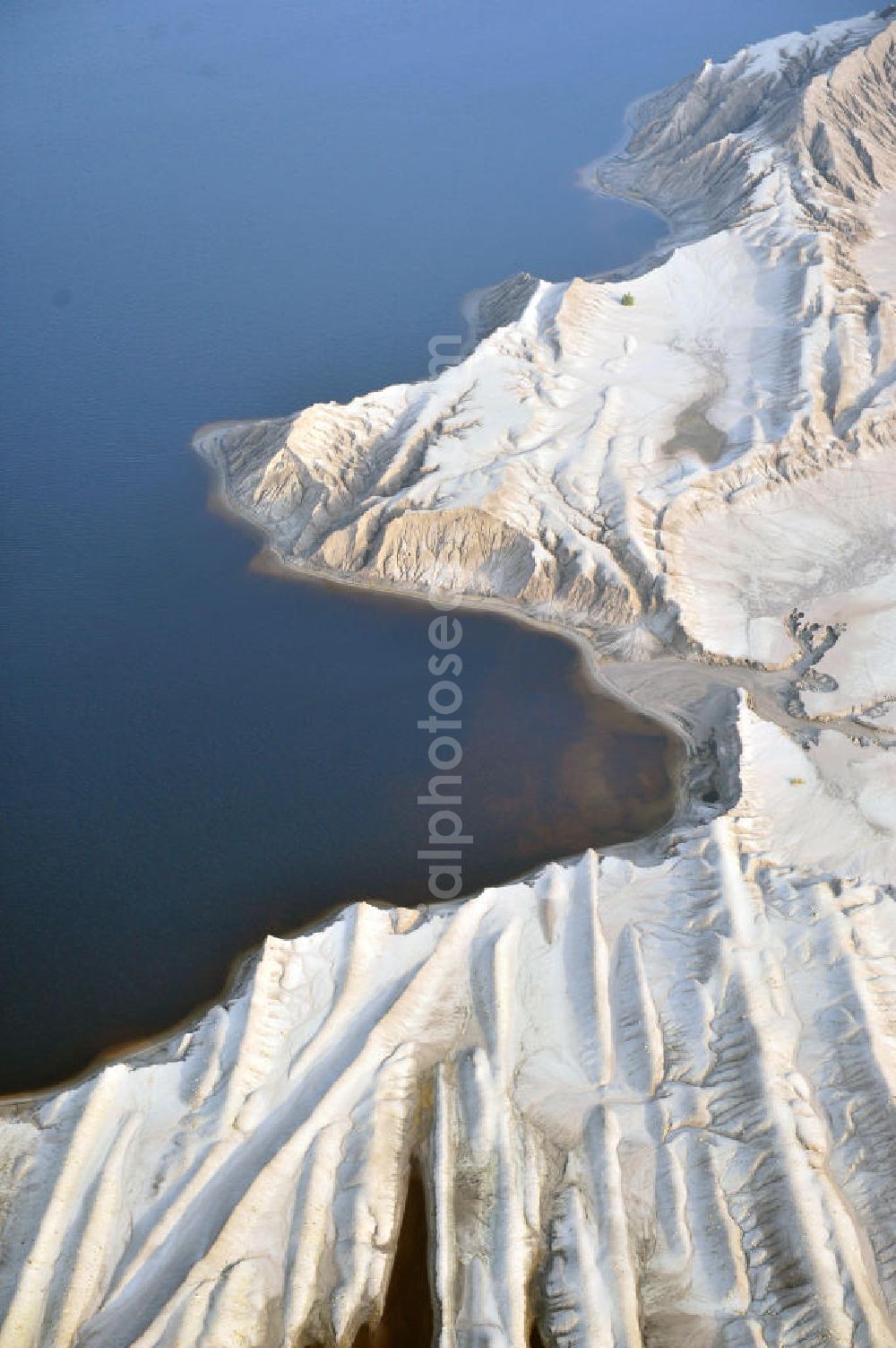 Aerial photograph Bluno - Tagebaulandschaft mit Abraumhalden am Blunoer Südsee (obersorbisch Juzny Blunjanski jezor) ist ein Tagebaurestsee der Lausitzer Seenkette im sächsischen Teil des Lausitzer Seenlandes, auf dem Gebiet der Gemeinde Elsterheide. Seinen Namen verdankt der See einerseits seiner Lage südlich des Ortes Bluno. Der See entstand durch Flutung des Restlochs „ Nordschlauch “ des Tagebaues Spreetal. Lusatian lake district in the Saxon part of the Lusatian Lake District.