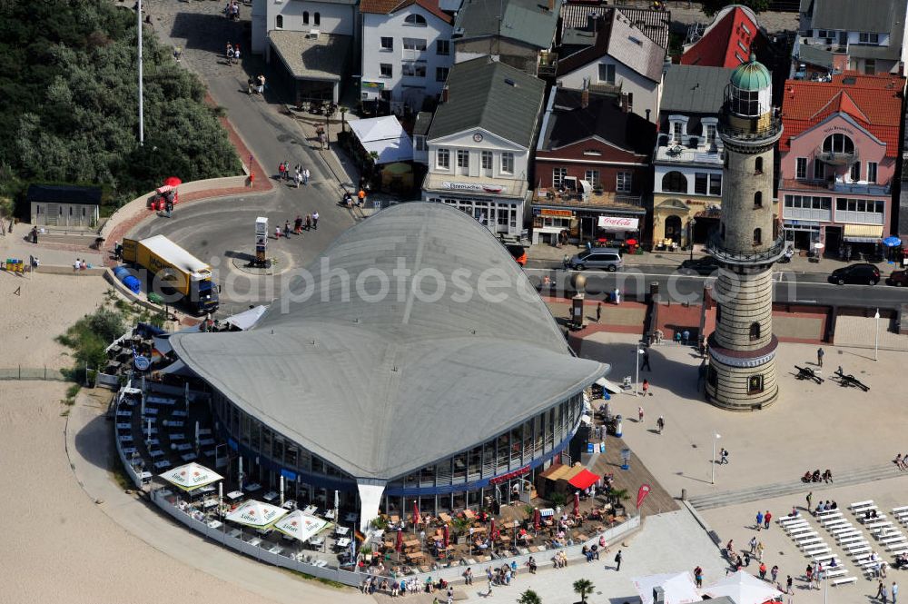 Aerial image Rostock - Warnemünde - Blick auf die den Teepott mit dem alten Leuchtturman der Seepromenade des Ostseestrandes von Warnemünde. Der 1967 errichtete Teepott neben dem Leuchtturm an der Warnemünder Seepromenade erbaute Einzelbau ist ein Beispiel für die Hyparschalenarchitektur der 1960er Jahre. Er beherbergt unter an derem zwei Restaurants und eine ständige Ausstellung des Weltenbummlers Reinhold Kasten. Views of the lake with the Teepott and the old lighthouse at the Baltic Sea beach of Warnemünde.