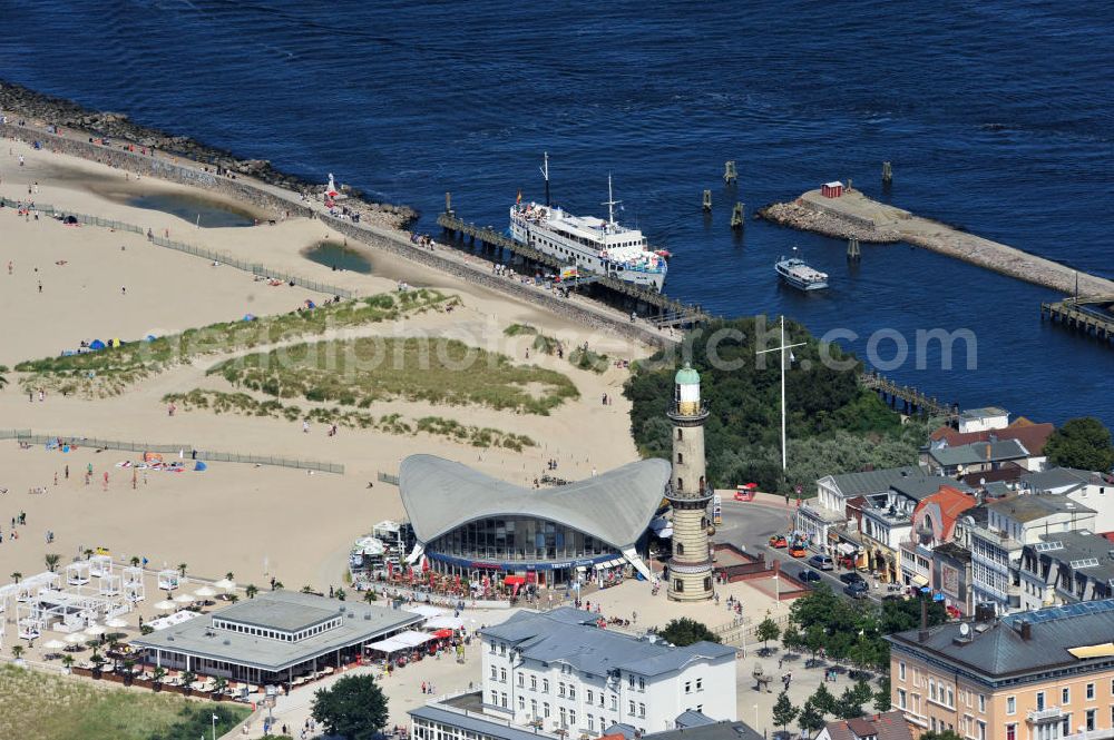 Aerial photograph Rostock - Warnemünde - Blick auf die den Teepott mit dem alten Leuchtturman der Seepromenade des Ostseestrandes von Warnemünde. Der 1967 errichtete Teepott neben dem Leuchtturm an der Warnemünder Seepromenade erbaute Einzelbau ist ein Beispiel für die Hyparschalenarchitektur der 1960er Jahre. Er beherbergt unter an derem zwei Restaurants und eine ständige Ausstellung des Weltenbummlers Reinhold Kasten. Views of the lake with the Teepott and the old lighthouse at the Baltic Sea beach of Warnemünde.