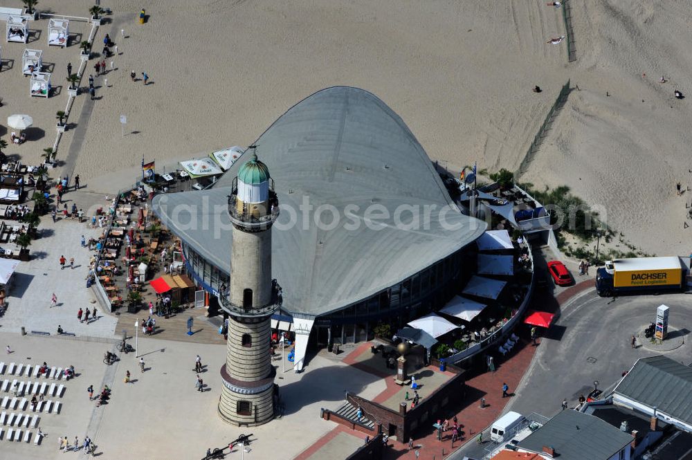 Aerial photograph Rostock - Warnemünde - Blick auf die den Teepott mit dem alten Leuchtturman der Seepromenade des Ostseestrandes von Warnemünde. Der 1967 errichtete Teepott neben dem Leuchtturm an der Warnemünder Seepromenade erbaute Einzelbau ist ein Beispiel für die Hyparschalenarchitektur der 1960er Jahre. Er beherbergt unter an derem zwei Restaurants und eine ständige Ausstellung des Weltenbummlers Reinhold Kasten. Views of the lake with the Teepott and the old lighthouse at the Baltic Sea beach of Warnemünde.