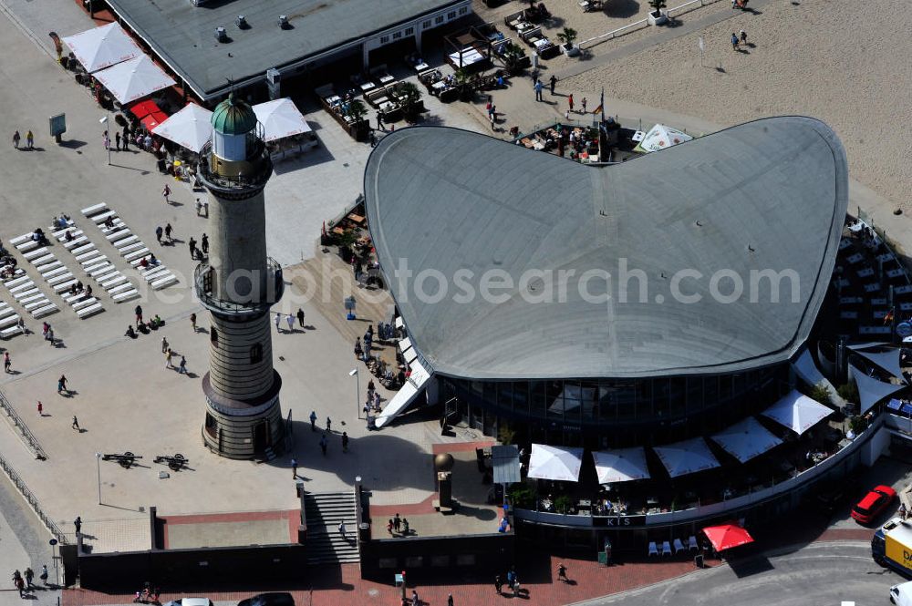 Rostock - Warnemünde from above - Blick auf die den Teepott mit dem alten Leuchtturman der Seepromenade des Ostseestrandes von Warnemünde. Der 1967 errichtete Teepott neben dem Leuchtturm an der Warnemünder Seepromenade erbaute Einzelbau ist ein Beispiel für die Hyparschalenarchitektur der 1960er Jahre. Er beherbergt unter an derem zwei Restaurants und eine ständige Ausstellung des Weltenbummlers Reinhold Kasten. Views of the lake with the Teepott and the old lighthouse at the Baltic Sea beach of Warnemünde.