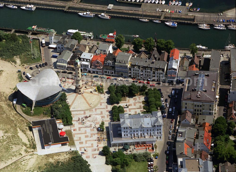 Aerial photograph Rostock - Warnemünde - Blick auf die den Teepott mit dem alten Leuchtturman der Seepromenade des Ostseestrandes von Warnemünde. Der 1967 errichtete Teepott neben dem Leuchtturm an der Warnemünder Seepromenade erbaute Einzelbau ist ein Beispiel für die Hyparschalenarchitektur der 1960er Jahre. Er beherbergt unter an derem zwei Restaurants und eine ständige Ausstellung des Weltenbummlers Reinhold Kasten. Views of the lake with the Teepott and the old lighthouse at the Baltic Sea beach of Warnemünde.