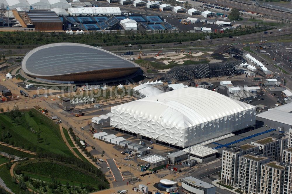London from above - Partial view of the Olympic Park in London. View of the Olympic Velodrome and the basketball arena. The Velodrome has been designed by the architect office Hopkins architects and built from 2009 to 2011 for bike competitions of the Summer Olympic Games in 2012. The white temporary basketball arena and sports facility was also built from 2009 to 2011 and is used for the preliminary round basketball and handball finals of the Olympic Games