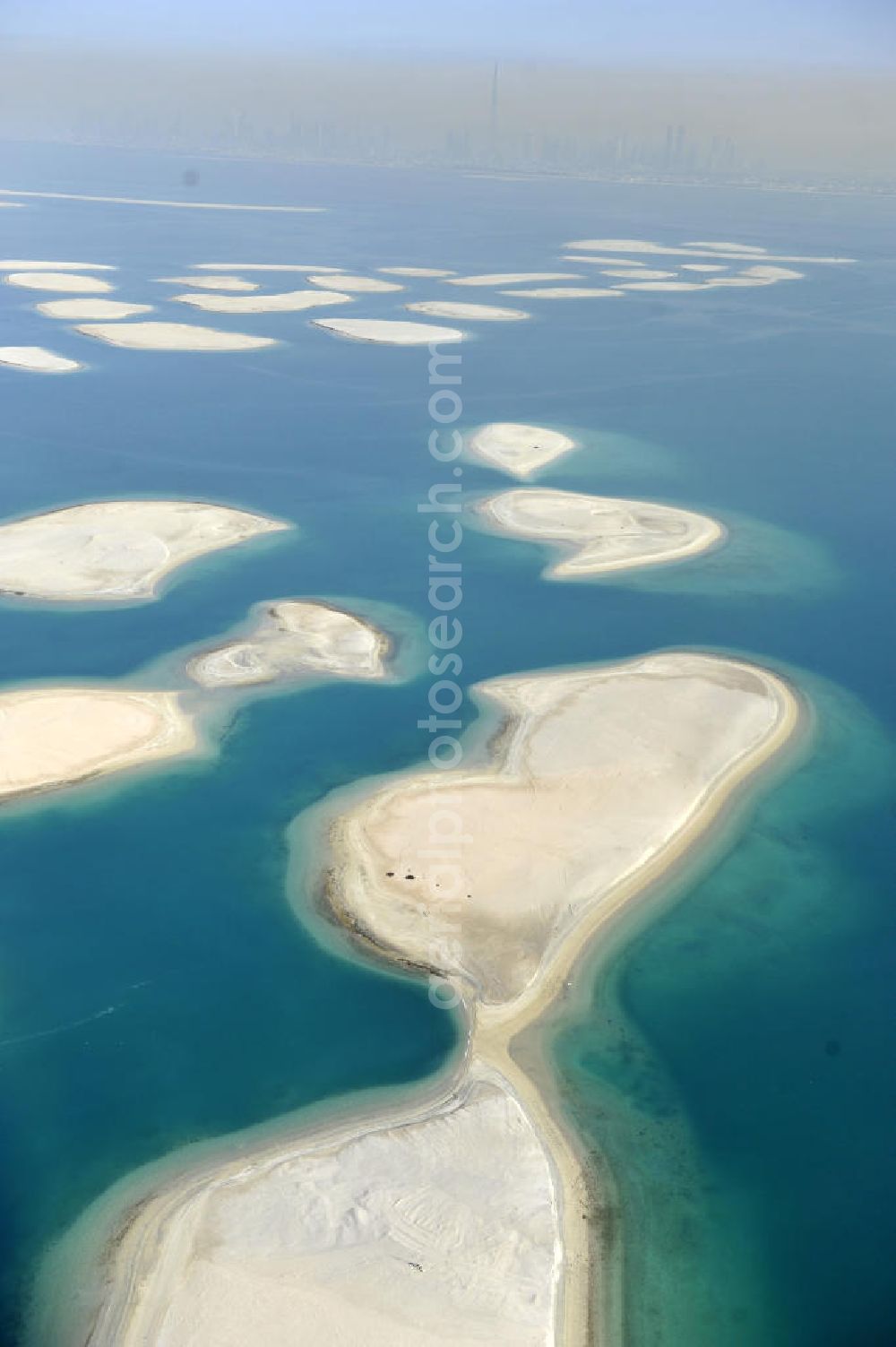 Dubai from above - Blick auf einen Teil der Inselgruppe The World. The World oder World Islands ist eine auf der Basis von Felsschüttungen aus verdichtetem Sand aufgespülte künstliche Inselgruppe, die die groben Umrisse der Weltkarte darstellen sollen. Sie befindet sich 4,0 km (2,5 Meilen) vor der Küste Dubais, Vereinigte Arabische Emirate und besteht aus mehreren verscheidenen kleineren Inseln. View of a part of the archipelago The World. The World or World Islands is an artificial archipelago of various small islands constructed in the rough shape of a world map, located 4,0 km (2.5 mi) off the coast of Dubai, United Arab Emirates.