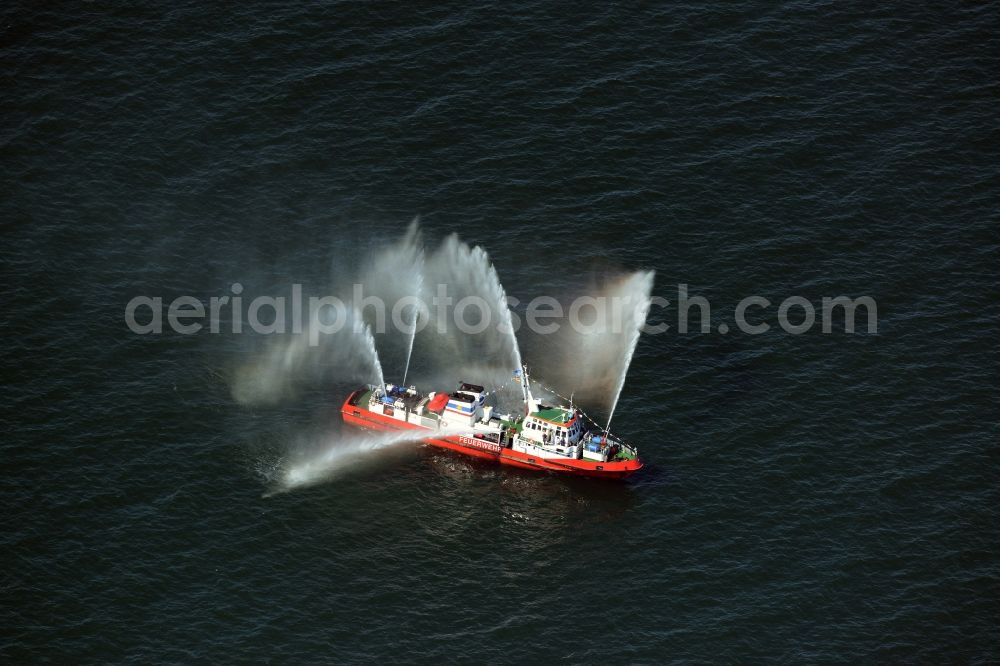 Rostock from above - Water fountains of traditional fire extinguishing ship welcoming the sailing ships of the Hanse Sail maritime leak on the Baltic Sea in Rostock in Mecklenburg - Western Pomerania