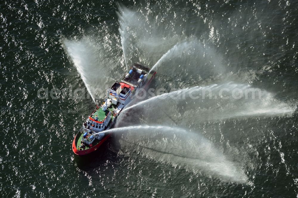 Aerial image Rostock - Water fountains of traditional fire extinguishing ship welcoming the sailing ships of the Hanse Sail maritime leak on the Baltic Sea in Rostock in Mecklenburg - Western Pomerania