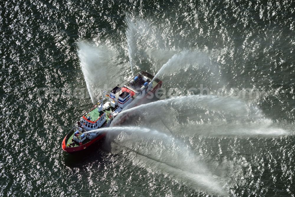 Aerial photograph Rostock - Water fountains of traditional fire extinguishing ship welcoming the sailing ships of the Hanse Sail maritime leak on the Baltic Sea in Rostock in Mecklenburg - Western Pomerania