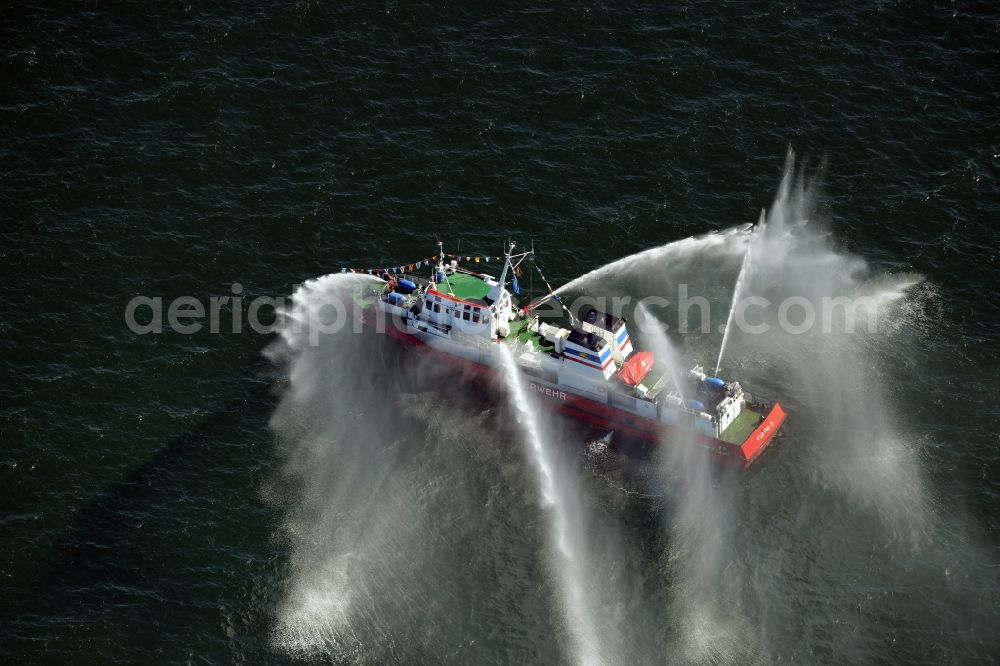 Rostock from above - Water fountains of traditional fire extinguishing ship welcoming the sailing ships of the Hanse Sail maritime leak on the Baltic Sea in Rostock in Mecklenburg - Western Pomerania