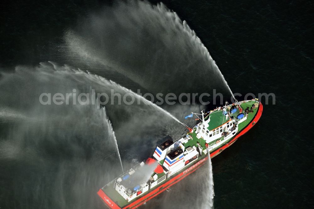 Aerial image Rostock - Water fountains of traditional fire extinguishing ship welcoming the sailing ships of the Hanse Sail maritime leak on the Baltic Sea in Rostock in Mecklenburg - Western Pomerania