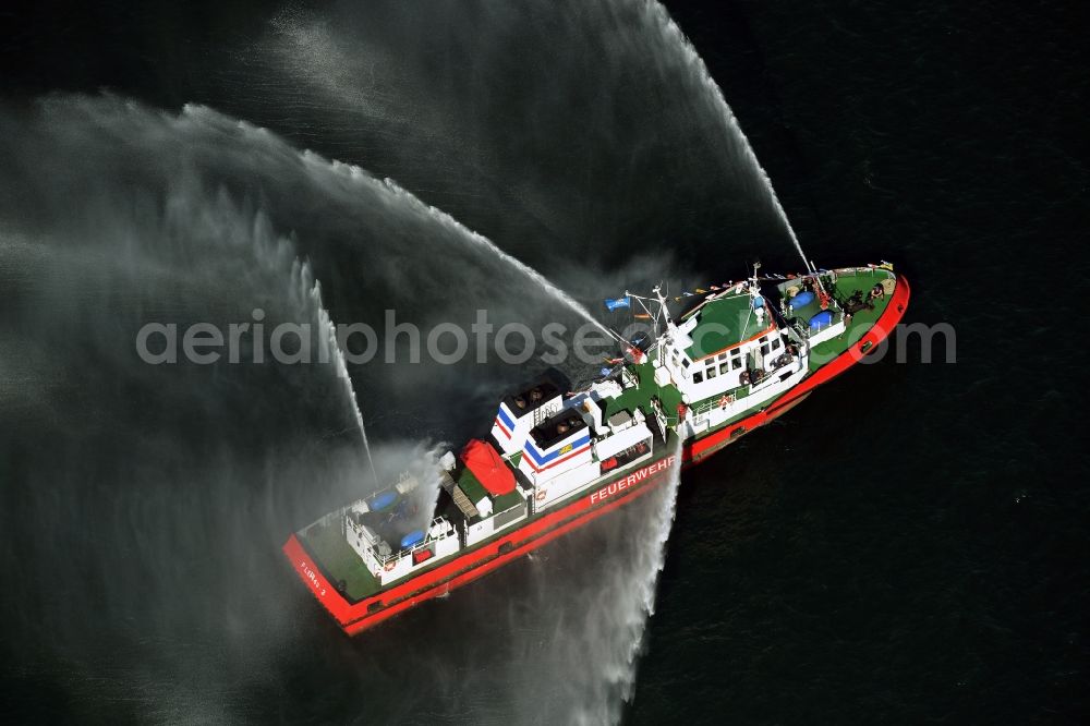 Aerial photograph Rostock - Water fountains of traditional fire extinguishing ship welcoming the sailing ships of the Hanse Sail maritime leak on the Baltic Sea in Rostock in Mecklenburg - Western Pomerania