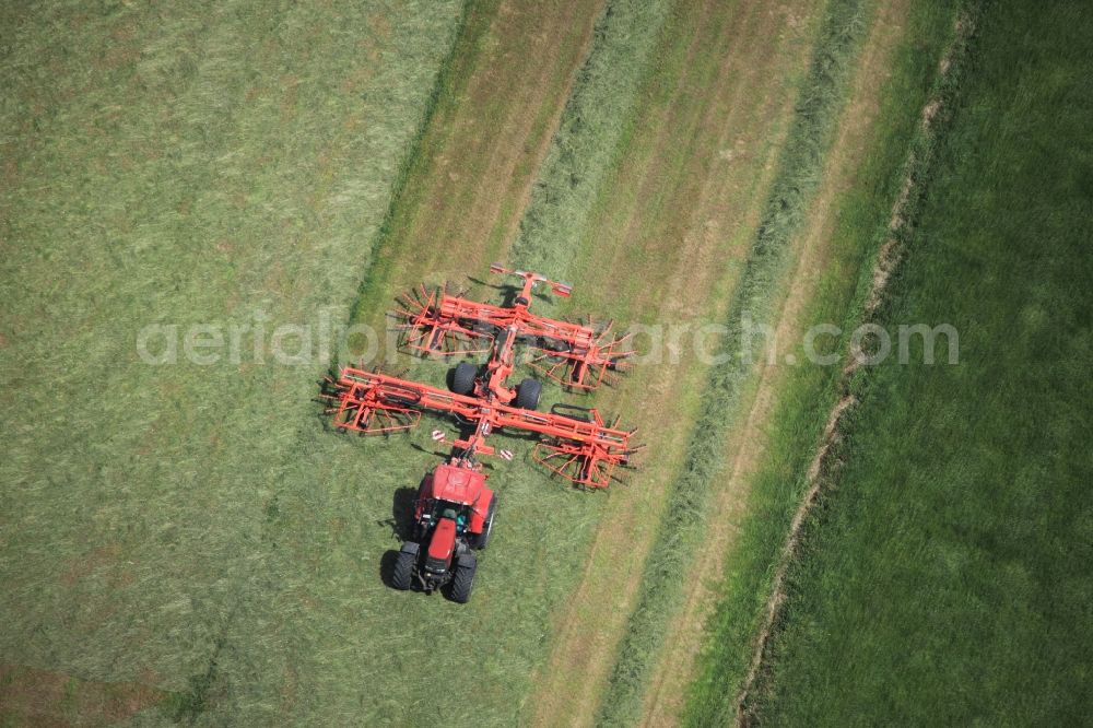 Rieseby from the bird's eye view: Tractor and agricultural field work in the Hoerst part of Rieseby in the state of Schleswig-Holstein. The island Schwansen is mostly used agriculturally. The red vehicle moves symmetrically through the field during harvest