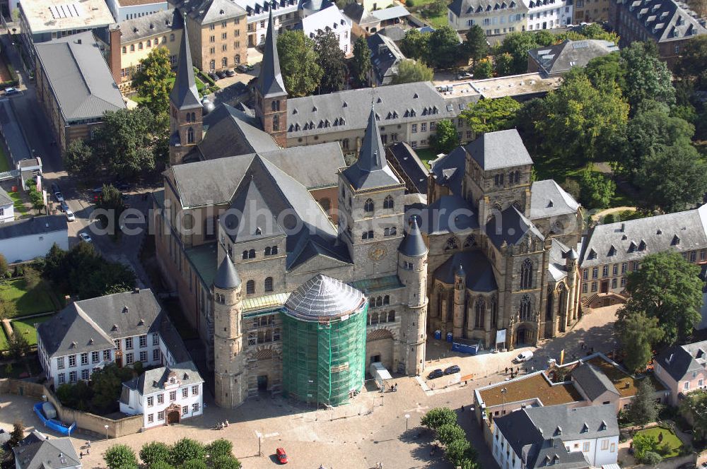 TRIER from the bird's eye view: Trierer Dom, St. Gangolf und die Liebfrauenkirche in Trier. Die Hohe Domkirche St. Peter zu Trier ist die älteste Bischofskirche Deutschlands und die Mutterkirche des Bistums Trier. Das bedeutende sakrale Bauwerk abendländischer Baukunst steht seit 1986 zusammen mit der unmittelbar benachbarten Liebfrauenkirche auf der UNESCO-Liste des Weltkulturerbes. Mit einer Länge von 112,5 Metern und einer Breite von 41 Metern ist der Dom das größte Kirchengebäude der Stadt Trier.Der Dom steht über den Resten eines prächtigen römischen Wohnhauses. Nach dem Übertritt des römischen Kaisers Konstantin zum Christentum wurde eine Basilika errichtet, die unter Bischof Maximin (329–346) zu einer der größten Kirchenanlagen Europas mit vier Basiliken, einem Baptisterium und Nebengebäuden erweitert wurde.