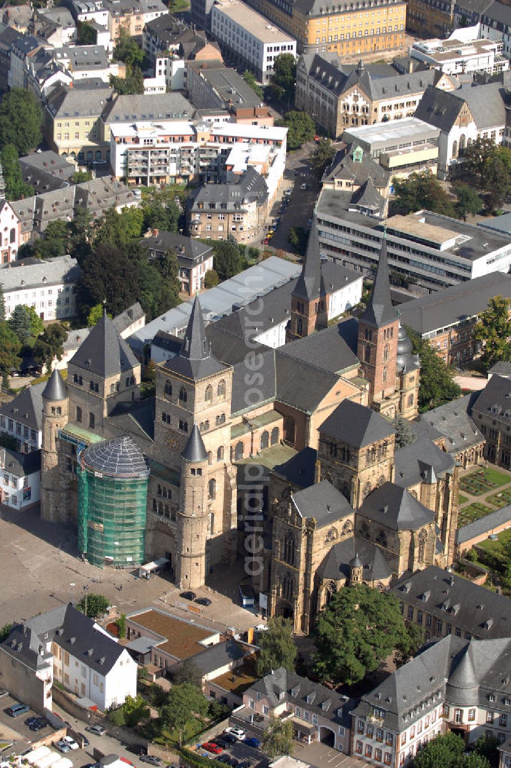 TRIER from above - Trierer Dom, St. Gangolf und die Liebfrauenkirche in Trier. Die Hohe Domkirche St. Peter zu Trier ist die älteste Bischofskirche Deutschlands und die Mutterkirche des Bistums Trier. Das bedeutende sakrale Bauwerk abendländischer Baukunst steht seit 1986 zusammen mit der unmittelbar benachbarten Liebfrauenkirche auf der UNESCO-Liste des Weltkulturerbes. Mit einer Länge von 112,5 Metern und einer Breite von 41 Metern ist der Dom das größte Kirchengebäude der Stadt Trier.Der Dom steht über den Resten eines prächtigen römischen Wohnhauses. Nach dem Übertritt des römischen Kaisers Konstantin zum Christentum wurde eine Basilika errichtet, die unter Bischof Maximin (329–346) zu einer der größten Kirchenanlagen Europas mit vier Basiliken, einem Baptisterium und Nebengebäuden erweitert wurde.