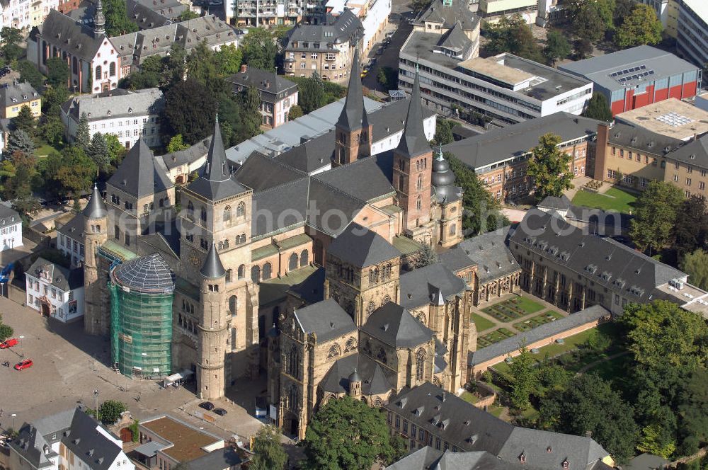 TRIER from the bird's eye view: Trierer Dom, St. Gangolf und die Liebfrauenkirche in Trier. Die Hohe Domkirche St. Peter zu Trier ist die älteste Bischofskirche Deutschlands und die Mutterkirche des Bistums Trier. Das bedeutende sakrale Bauwerk abendländischer Baukunst steht seit 1986 zusammen mit der unmittelbar benachbarten Liebfrauenkirche auf der UNESCO-Liste des Weltkulturerbes. Mit einer Länge von 112,5 Metern und einer Breite von 41 Metern ist der Dom das größte Kirchengebäude der Stadt Trier.Der Dom steht über den Resten eines prächtigen römischen Wohnhauses. Nach dem Übertritt des römischen Kaisers Konstantin zum Christentum wurde eine Basilika errichtet, die unter Bischof Maximin (329–346) zu einer der größten Kirchenanlagen Europas mit vier Basiliken, einem Baptisterium und Nebengebäuden erweitert wurde.