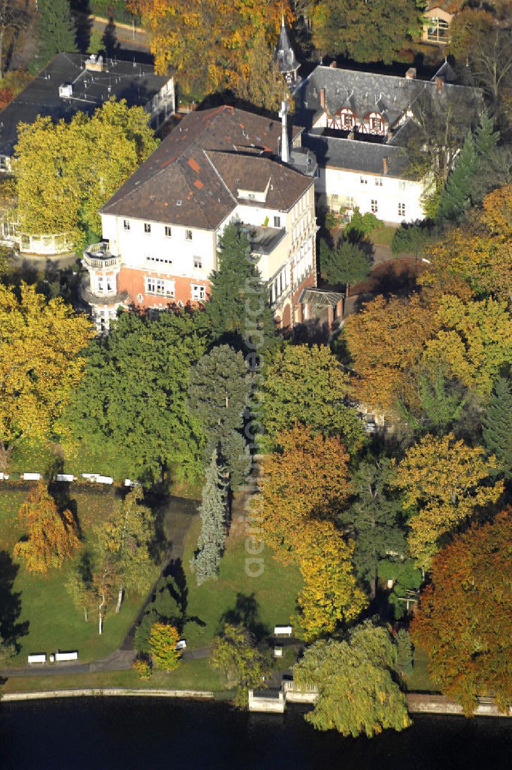 Aerial image Berlin - Blick auf den uferbereich an der Villa Siemens Am Kleinen Wannsee direkt gegenüber des Neubaus zum Immanuel-Krankenhauses in Berlin-Wannsee. Das Krankenhaus gehört zur Immanuel Diakonie Group (IDG), die eine Einrichtung der Evangelisch-Freikirchlichen Gemeinde Berlin-Schöneberg ist. Die Verwaltung der IDG hatte ihren Sitz in der Villa Siemens. Das Gebäude war einst eine Sommerresidenz von Arnold von Siemens, dem ältesten Sohn des Firmengründers Werner von Siemens. Die Architekten waren Paul und Walther Hentschel, 1888 wurde der Bau fertiggestellt. Die Villa Siemens gehörte zur Colonie Alsen, einer Siedlung für das Berliner Großbürgertum, die Wilhelm Conrad 1863 gegründet hatte. Nach dem Zweiten Weltkrieg stifteten Hermann und Charlotte von Siemens die Villa der Baptisten-Gemeinde mit der Auflage, sie für soziale Zwecke zu nutzen. Es ist das einzige Ensemble von Gebäude und Park der ehemaligen Kolonie, das bis heute erhalten geblieben ist. Der Krankenhausbetrieb ist jetzt in einem Neubau auf der gegenüberliegenden Straßenseite untergebracht. Das ehemals zum Areal gehörende Anwesen Am kleinen Wannsee Nr 4 wurde verkauft. ISA Immobilien Service Agentur GmbH, Herr Roland Kober