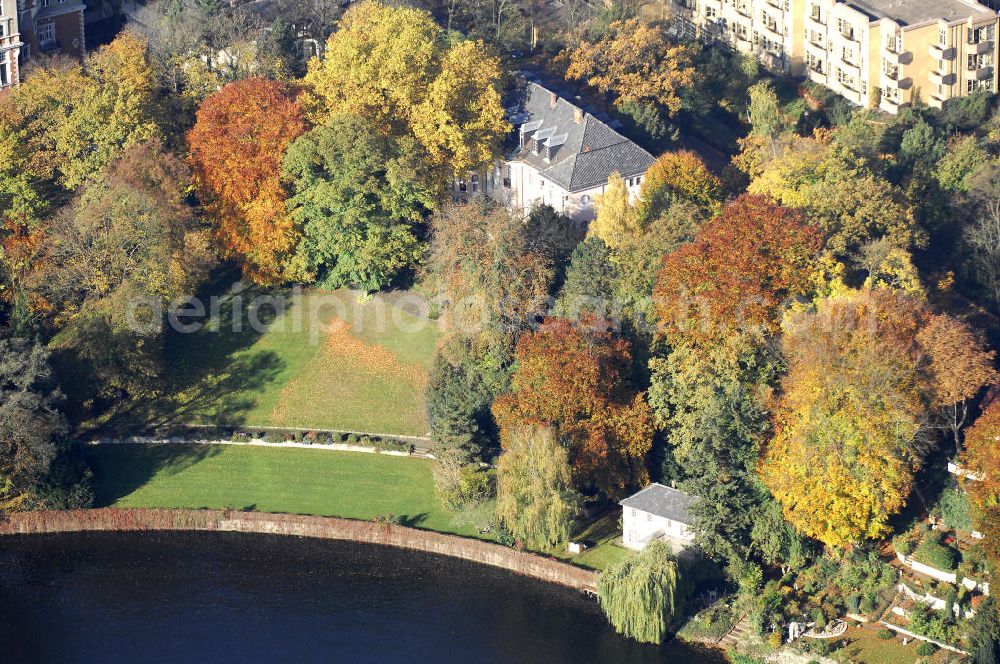 Aerial photograph Berlin - Blick auf den uferbereich an der Villa Siemens Am Kleinen Wannsee direkt gegenüber des Neubaus zum Immanuel-Krankenhauses in Berlin-Wannsee. Das Krankenhaus gehört zur Immanuel Diakonie Group (IDG), die eine Einrichtung der Evangelisch-Freikirchlichen Gemeinde Berlin-Schöneberg ist. Die Verwaltung der IDG hatte ihren Sitz in der Villa Siemens. Das Gebäude war einst eine Sommerresidenz von Arnold von Siemens, dem ältesten Sohn des Firmengründers Werner von Siemens. Die Architekten waren Paul und Walther Hentschel, 1888 wurde der Bau fertiggestellt. Die Villa Siemens gehörte zur Colonie Alsen, einer Siedlung für das Berliner Großbürgertum, die Wilhelm Conrad 1863 gegründet hatte. Nach dem Zweiten Weltkrieg stifteten Hermann und Charlotte von Siemens die Villa der Baptisten-Gemeinde mit der Auflage, sie für soziale Zwecke zu nutzen. Es ist das einzige Ensemble von Gebäude und Park der ehemaligen Kolonie, das bis heute erhalten geblieben ist. Der Krankenhausbetrieb ist jetzt in einem Neubau auf der gegenüberliegenden Straßenseite untergebracht. Das ehemals zum Areal gehörende Anwesen Am kleinen Wannsee Nr 4 wurde verkauft. ISA Immobilien Service Agentur GmbH, Herr Roland Kober