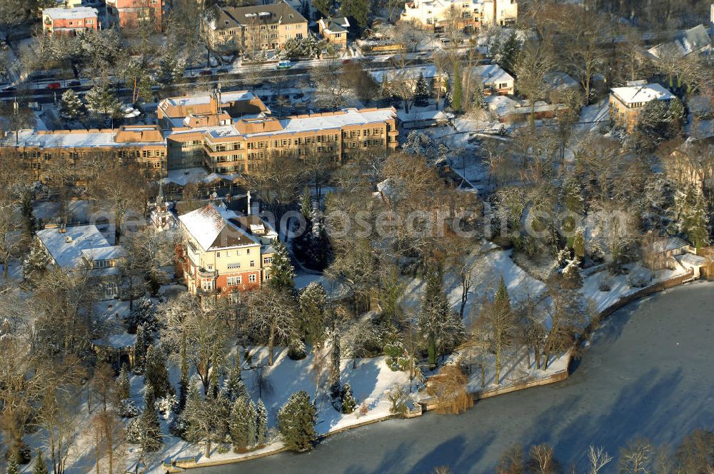 Berlin from the bird's eye view: Blick auf den winterlich mit Schnee bedeckten Uferbereich an der Villa Siemens Am Kleinen Wannsee direkt gegenüber des Neubaus zum Immanuel-Krankenhauses in Berlin-Wannsee. Das Krankenhaus gehört zur Immanuel Diakonie Group (IDG), die eine Einrichtung der Evangelisch-Freikirchlichen Gemeinde Berlin-Schöneberg ist. Die Verwaltung der IDG hatte ihren Sitz in der Villa Siemens. Das Gebäude war einst eine Sommerresidenz von Arnold von Siemens, dem ältesten Sohn des Firmengründers Werner von Siemens. Die Architekten waren Paul und Walther Hentschel, 1888 wurde der Bau fertiggestellt. Die Villa Siemens gehörte zur Colonie Alsen, einer Siedlung für das Berliner Großbürgertum, die Wilhelm Conrad 1863 gegründet hatte. Nach dem Zweiten Weltkrieg stifteten Hermann und Charlotte von Siemens die Villa der Baptisten-Gemeinde mit der Auflage, sie für soziale Zwecke zu nutzen. Es ist das einzige Ensemble von Gebäude und Park der ehemaligen Kolonie, das bis heute erhalten geblieben ist. Der Krankenhausbetrieb ist jetzt in einem Neubau auf der gegenüberliegenden Straßenseite untergebracht. Das ehemals zum Areal gehörende Anwesen Am kleinen Wannsee Nr 4 wurde verkauft. ISA IMMOBILEN AGENTUR GmbH, Herr Roland Kober