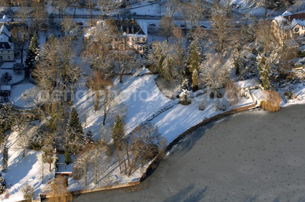 Berlin from the bird's eye view: Blick auf den winterlich mit Schnee bedeckten Uferbereich an der Villa Siemens Am Kleinen Wannsee direkt gegenüber des Neubaus zum Immanuel-Krankenhauses in Berlin-Wannsee. Das Krankenhaus gehört zur Immanuel Diakonie Group (IDG), die eine Einrichtung der Evangelisch-Freikirchlichen Gemeinde Berlin-Schöneberg ist. Die Verwaltung der IDG hatte ihren Sitz in der Villa Siemens. Das Gebäude war einst eine Sommerresidenz von Arnold von Siemens, dem ältesten Sohn des Firmengründers Werner von Siemens. Die Architekten waren Paul und Walther Hentschel, 1888 wurde der Bau fertiggestellt. Die Villa Siemens gehörte zur Colonie Alsen, einer Siedlung für das Berliner Großbürgertum, die Wilhelm Conrad 1863 gegründet hatte. Nach dem Zweiten Weltkrieg stifteten Hermann und Charlotte von Siemens die Villa der Baptisten-Gemeinde mit der Auflage, sie für soziale Zwecke zu nutzen. Es ist das einzige Ensemble von Gebäude und Park der ehemaligen Kolonie, das bis heute erhalten geblieben ist. Der Krankenhausbetrieb ist jetzt in einem Neubau auf der gegenüberliegenden Straßenseite untergebracht. Das ehemals zum Areal gehörende Anwesen Am kleinen Wannsee Nr 4 wurde verkauft. ISA IMMOBILEN AGENTUR GmbH, Herr Roland Kober