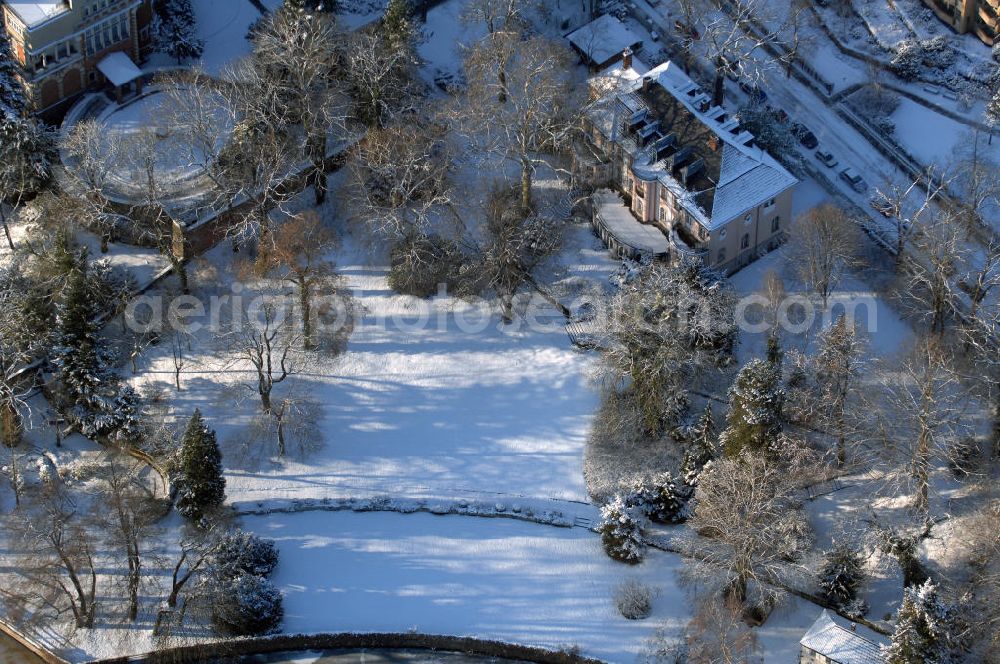 Berlin from above - Blick auf den winterlich mit Schnee bedeckten Uferbereich an der Villa Siemens Am Kleinen Wannsee direkt gegenüber des Neubaus zum Immanuel-Krankenhauses in Berlin-Wannsee. Das Krankenhaus gehört zur Immanuel Diakonie Group (IDG), die eine Einrichtung der Evangelisch-Freikirchlichen Gemeinde Berlin-Schöneberg ist. Die Verwaltung der IDG hatte ihren Sitz in der Villa Siemens. Das Gebäude war einst eine Sommerresidenz von Arnold von Siemens, dem ältesten Sohn des Firmengründers Werner von Siemens. Die Architekten waren Paul und Walther Hentschel, 1888 wurde der Bau fertiggestellt. Die Villa Siemens gehörte zur Colonie Alsen, einer Siedlung für das Berliner Großbürgertum, die Wilhelm Conrad 1863 gegründet hatte. Nach dem Zweiten Weltkrieg stifteten Hermann und Charlotte von Siemens die Villa der Baptisten-Gemeinde mit der Auflage, sie für soziale Zwecke zu nutzen. Es ist das einzige Ensemble von Gebäude und Park der ehemaligen Kolonie, das bis heute erhalten geblieben ist. Der Krankenhausbetrieb ist jetzt in einem Neubau auf der gegenüberliegenden Straßenseite untergebracht. Das ehemals zum Areal gehörende Anwesen Am kleinen Wannsee Nr 4 wurde verkauft. ISA IMMOBILEN AGENTUR GmbH, Herr Roland Kober