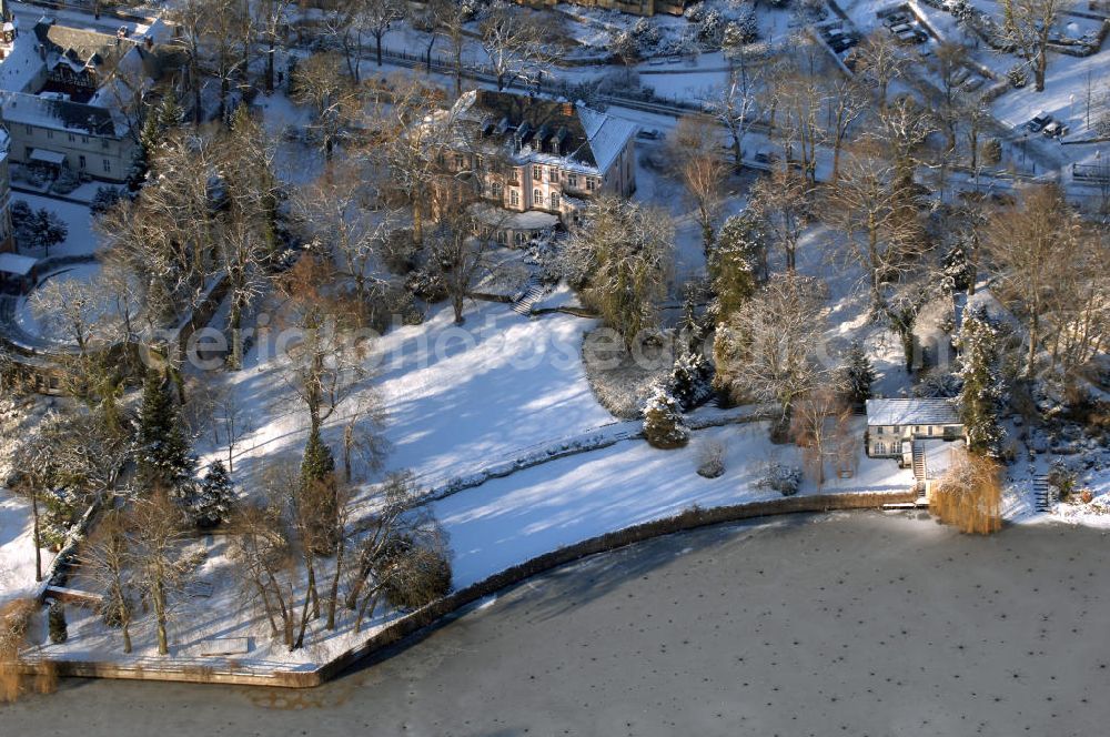 Berlin from above - Blick auf den winterlich mit Schnee bedeckten Uferbereich an der Villa Siemens Am Kleinen Wannsee direkt gegenüber des Neubaus zum Immanuel-Krankenhauses in Berlin-Wannsee. Das Krankenhaus gehört zur Immanuel Diakonie Group (IDG), die eine Einrichtung der Evangelisch-Freikirchlichen Gemeinde Berlin-Schöneberg ist. Die Verwaltung der IDG hatte ihren Sitz in der Villa Siemens. Das Gebäude war einst eine Sommerresidenz von Arnold von Siemens, dem ältesten Sohn des Firmengründers Werner von Siemens. Die Architekten waren Paul und Walther Hentschel, 1888 wurde der Bau fertiggestellt. Die Villa Siemens gehörte zur Colonie Alsen, einer Siedlung für das Berliner Großbürgertum, die Wilhelm Conrad 1863 gegründet hatte. Nach dem Zweiten Weltkrieg stifteten Hermann und Charlotte von Siemens die Villa der Baptisten-Gemeinde mit der Auflage, sie für soziale Zwecke zu nutzen. Es ist das einzige Ensemble von Gebäude und Park der ehemaligen Kolonie, das bis heute erhalten geblieben ist. Der Krankenhausbetrieb ist jetzt in einem Neubau auf der gegenüberliegenden Straßenseite untergebracht. Das ehemals zum Areal gehörende Anwesen Am kleinen Wannsee Nr 4 wurde verkauft. ISA IMMOBILEN AGENTUR GmbH, Herr Roland Kober