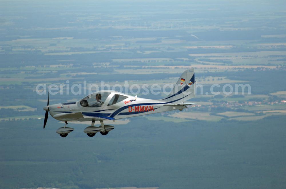 Aerial photograph Reckenthin - Ein modernes Ganzmetall-Ultraleichtflugzeug Eurostar über dem brandenburgischen Reckenthin. Es ist ein 2-Sitziges Ultraleichtflugzeug, das von der Firma Evektor-Aerotechnik aus Kunovice in Tschechien hergestellt wird und ab 1997 in den deutschen Markt eingeführt wurde. Nach Deutschland wird das Flugzeug vom Flugsportzentrum in Bautzen importiert.Das Flugzeug ist eine moderne Tiefdeckerkonstruktion aus Aluminium. Es hat eine Gleitzahl 1:10 und wird ständig verbessert. Letzte größere Änderungen erfolgten 2004 mit der Zulassung einer Variante mit der Bezeichnung Modell 2000/R für eine Startmasse von 472,5 kg Angetrieben wird der Eurostar von einem Rotax-Motor mit 80 bzw 100 PS. Von seinen Flugleistungen und seinem Platzangebot ist er vergleichbar mit kleinen 2-sitzigen Flugzeugen.