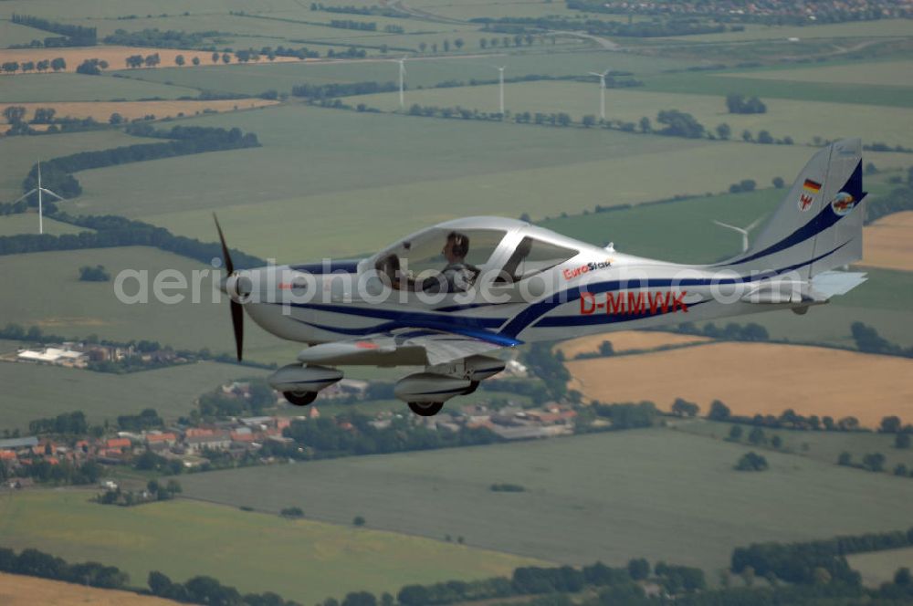 Aerial image Reckenthin - Ein modernes Ganzmetall-Ultraleichtflugzeug Eurostar über dem brandenburgischen Reckenthin. Es ist ein 2-Sitziges Ultraleichtflugzeug, das von der Firma Evektor-Aerotechnik aus Kunovice in Tschechien hergestellt wird und ab 1997 in den deutschen Markt eingeführt wurde. Nach Deutschland wird das Flugzeug vom Flugsportzentrum in Bautzen importiert.Das Flugzeug ist eine moderne Tiefdeckerkonstruktion aus Aluminium. Es hat eine Gleitzahl 1:10 und wird ständig verbessert. Letzte größere Änderungen erfolgten 2004 mit der Zulassung einer Variante mit der Bezeichnung Modell 2000/R für eine Startmasse von 472,5 kg Angetrieben wird der Eurostar von einem Rotax-Motor mit 80 bzw 100 PS. Von seinen Flugleistungen und seinem Platzangebot ist er vergleichbar mit kleinen 2-sitzigen Flugzeugen.