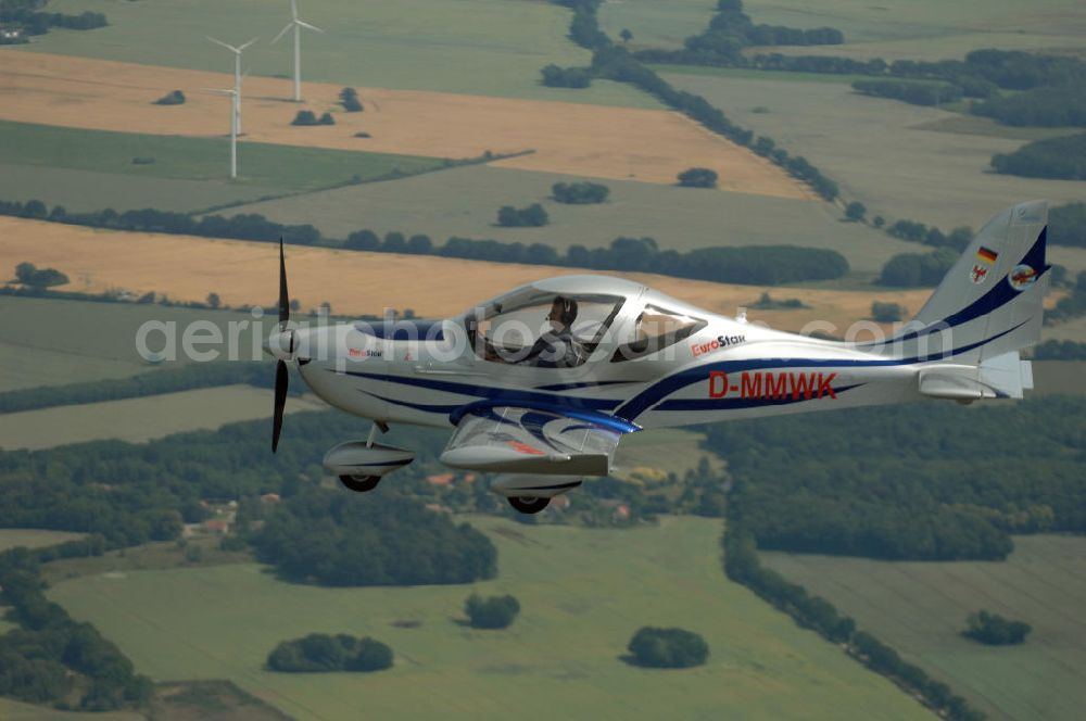 Reckenthin from the bird's eye view: Ein modernes Ganzmetall-Ultraleichtflugzeug Eurostar über dem brandenburgischen Reckenthin. Es ist ein 2-Sitziges Ultraleichtflugzeug, das von der Firma Evektor-Aerotechnik aus Kunovice in Tschechien hergestellt wird und ab 1997 in den deutschen Markt eingeführt wurde. Nach Deutschland wird das Flugzeug vom Flugsportzentrum in Bautzen importiert.Das Flugzeug ist eine moderne Tiefdeckerkonstruktion aus Aluminium. Es hat eine Gleitzahl 1:10 und wird ständig verbessert. Letzte größere Änderungen erfolgten 2004 mit der Zulassung einer Variante mit der Bezeichnung Modell 2000/R für eine Startmasse von 472,5 kg Angetrieben wird der Eurostar von einem Rotax-Motor mit 80 bzw 100 PS. Von seinen Flugleistungen und seinem Platzangebot ist er vergleichbar mit kleinen 2-sitzigen Flugzeugen.