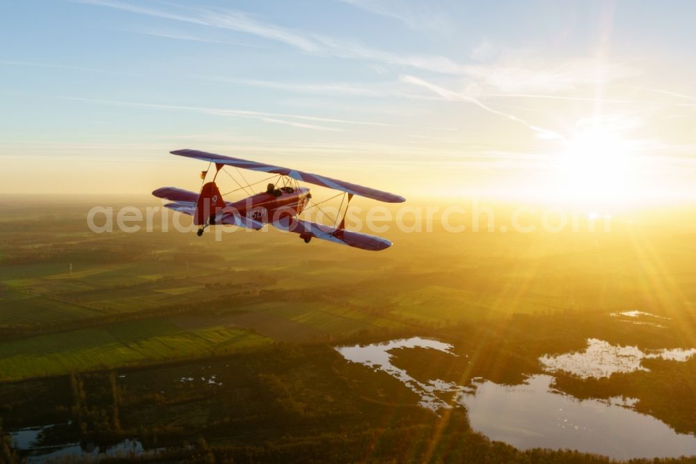 Oldendorf from the bird's eye view: Microlight aircraft Sunwheel D-MSLM while sunset over the lakes of moor near Oldendorf in Lower Saxony, Germany