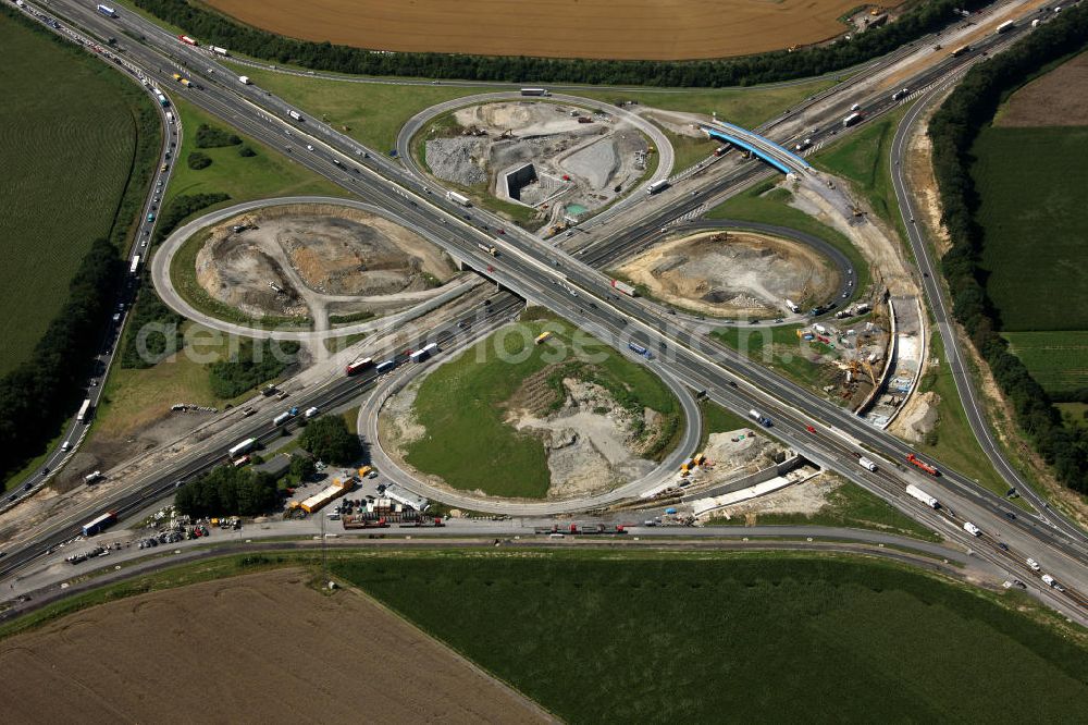 Aerial image Kamen - Das Kamener Kreuz ist das zweiteälteste Autobahnkreuz in Kleeblattform Deutschlands und dient der Verbindung der ersten Autobahnen des Landes, der A 1 (Nord-Süd-Richtung) und der A 2 (Ost-West-Richtung). Seine Einweihung fand 1937 statt. Das Autobahnkreuz liegt im Nordosten des Ruhrgebiets bei Kamen und Bergkamen zwischen den Großstädten Dortmund und Hamm und ist auch aufgrund der hier aufeinan dertreffenden wichtigen Verkehrsachsen ein überaus stark befahrener Verkehrsknotenpunkt. Die meisten Autofahrer kennen das Kamener Kreuz über die Staumeldungen der Verkehrsrundfunksender. Das Kamener Kreuz wird täglich von 160.000 Fahrzeugen befahren. Zur Zeit wird das Kamener Kreuz ausgebaut. Die Fertigstellung soll Ende 2009 sein. Das Kreuz wird dann von allen Seiten sechsspurig zu befahren sein. Eine besondere Herausforderung hierbei ist der Abriss und komplette Neubau der A 1-Brücke, die täglich von 90.000 Fahrzeugen befahren wird. Das Kreuz wird dann seine klassische Kleeblattform verlieren, da der Verkehr von der A 2 aus Richtung Hannover über eine Rampe auf die A 1 in Richtung Köln geleitet wird. Ausführende Firmen sind OEVERMANN, Münster Verkehrswegebau und Schäfer