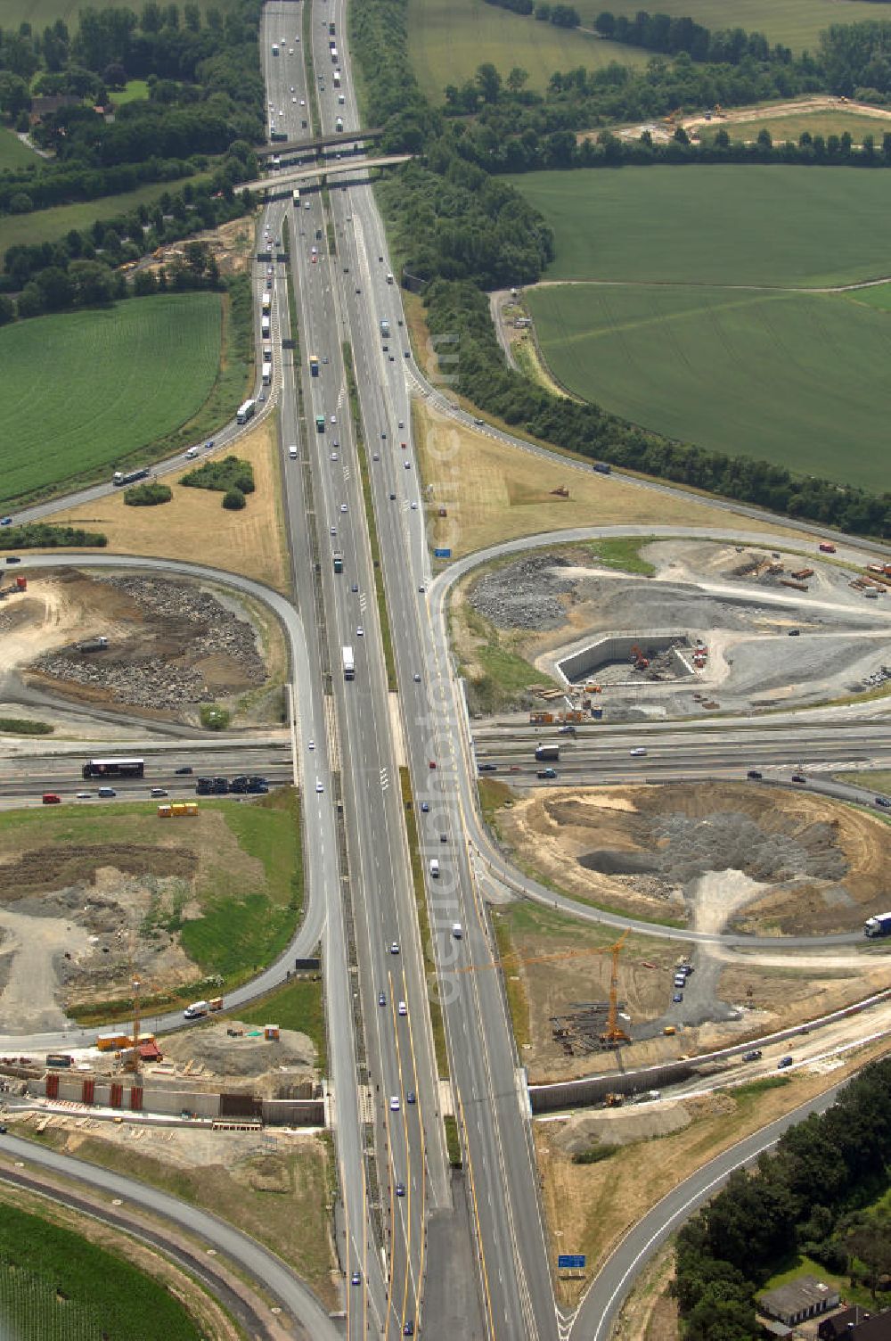 Aerial photograph KAMEN - Das Kamener Kreuz ist das zweiteälteste Autobahnkreuz in Kleeblattform Deutschlands und dient der Verbindung der ersten Autobahnen des Landes, der A 1 (Nord-Süd-Richtung) und der A 2 (Ost-West-Richtung). Seine Einweihung fand 1937 statt. Das Autobahnkreuz liegt im Nordosten des Ruhrgebiets bei Kamen und Bergkamen zwischen den Großstädten Dortmund und Hamm und ist auch aufgrund der hier aufeinan dertreffenden wichtigen Verkehrsachsen ein überaus stark befahrener Verkehrsknotenpunkt. Die meisten Autofahrer kennen das Kamener Kreuz über die Staumeldungen der Verkehrsrundfunksender. Das Kamener Kreuz wird täglich von 160.000 Fahrzeugen befahren. Zur Zeit wird das Kamener Kreuz ausgebaut. Die Fertigstellung soll Ende 2009 sein. Das Kreuz wird dann von allen Seiten sechsspurig zu befahren sein. Eine besondere Herausforderung hierbei ist der Abriss und komplette Neubau der A 1-Brücke, die täglich von 90.000 Fahrzeugen befahren wird. Das Kreuz wird dann seine klassische Kleeblattform verlieren, da der Verkehr von der A 2 aus Richtung Hannover über eine Rampe auf die A 1 in Richtung Köln geleitet wird. Ausführende Firmen sind OEVERMANN, Münster Verkehrswegebau und Schäfer